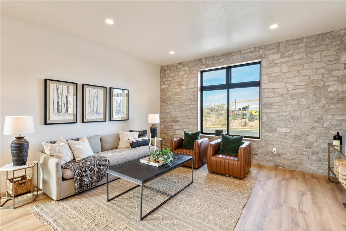 Living area with a stone accent wall, large picture window, recessed lighting, and wood-finish flooring