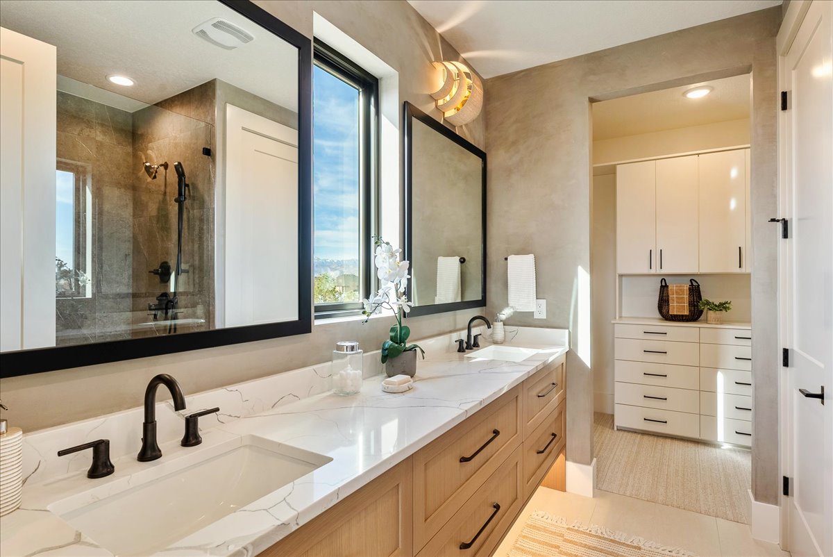 Dual vanity with light wood-finish cabinetry, quartz countertops, and matte black fixtures
