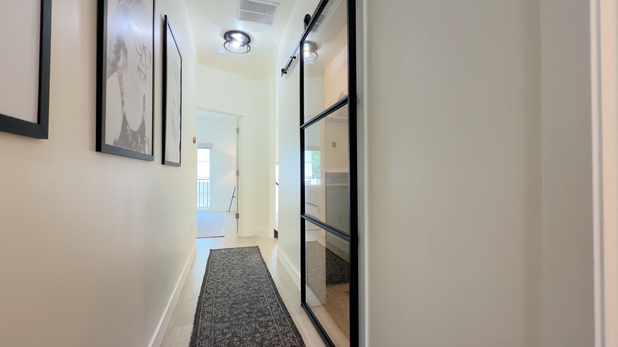 Hallway featuring wood-finish flooring, recessed lighting, and a modern barn door with glass panels