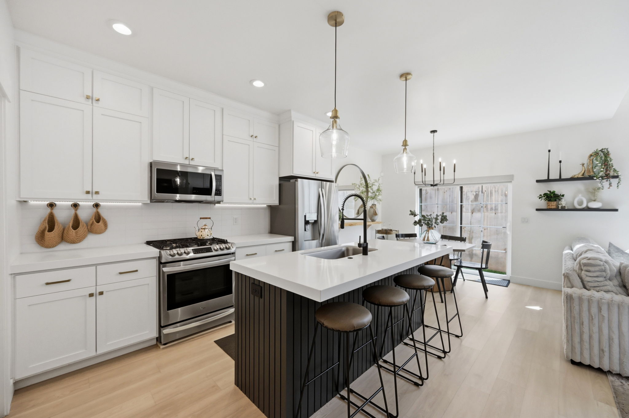 Contemporary kitchen featuring white shaker cabinetry, stainless steel appliances, and a central island with a white quartz countertop