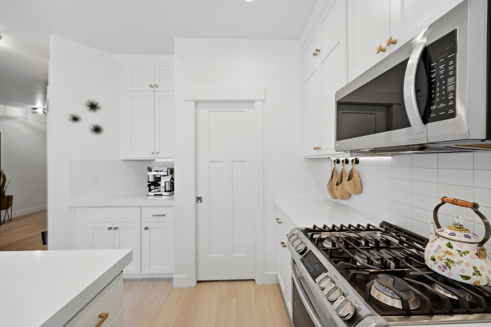 Bright kitchen featuring white shaker cabinetry, stainless steel microwave, gas range with griddle, and white subway tile backsplash