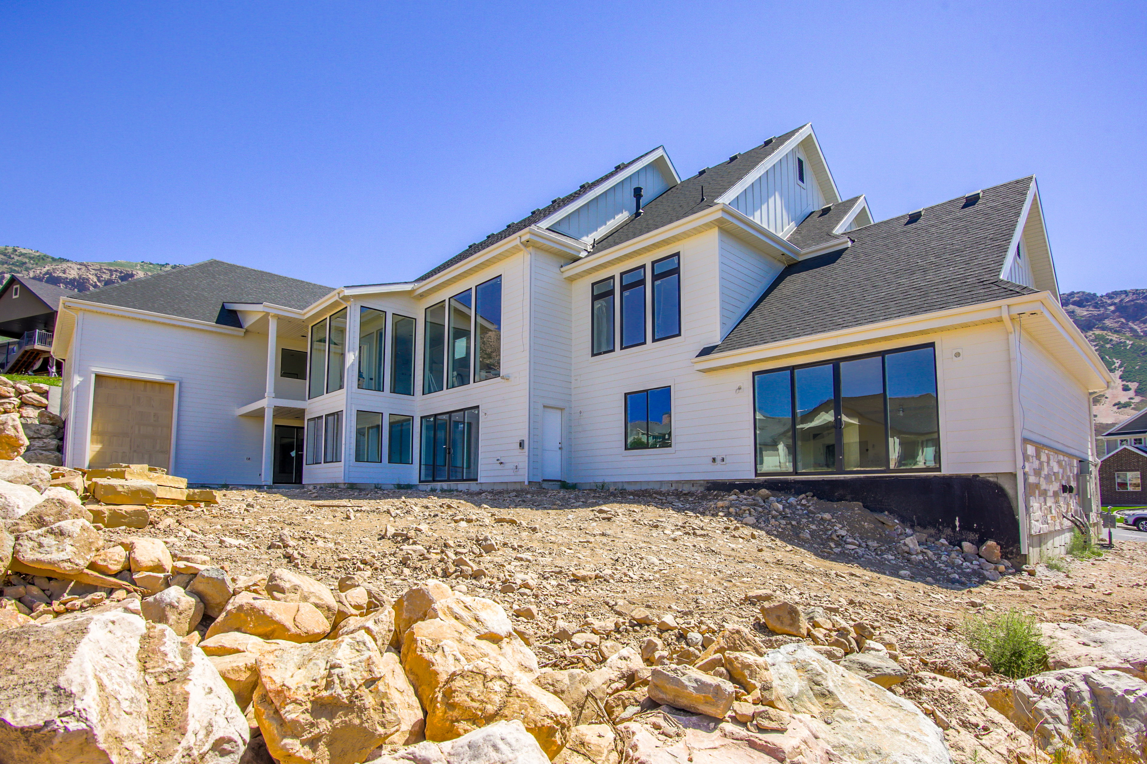 Contemporary multi-level residence featuring white siding and a dark shingle roof