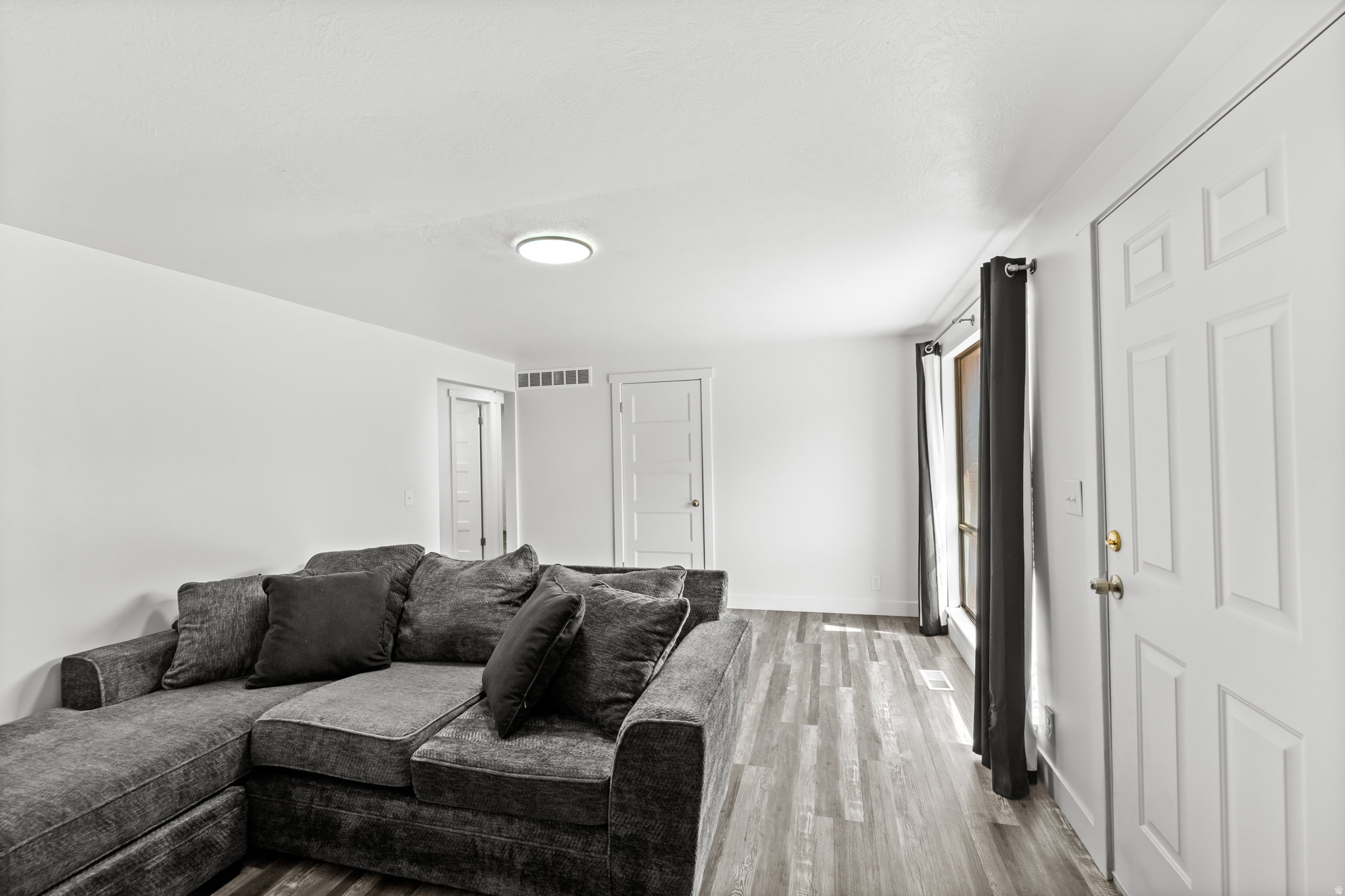 Bright interior space featuring wood-finish flooring and a contemporary flush-mount ceiling light