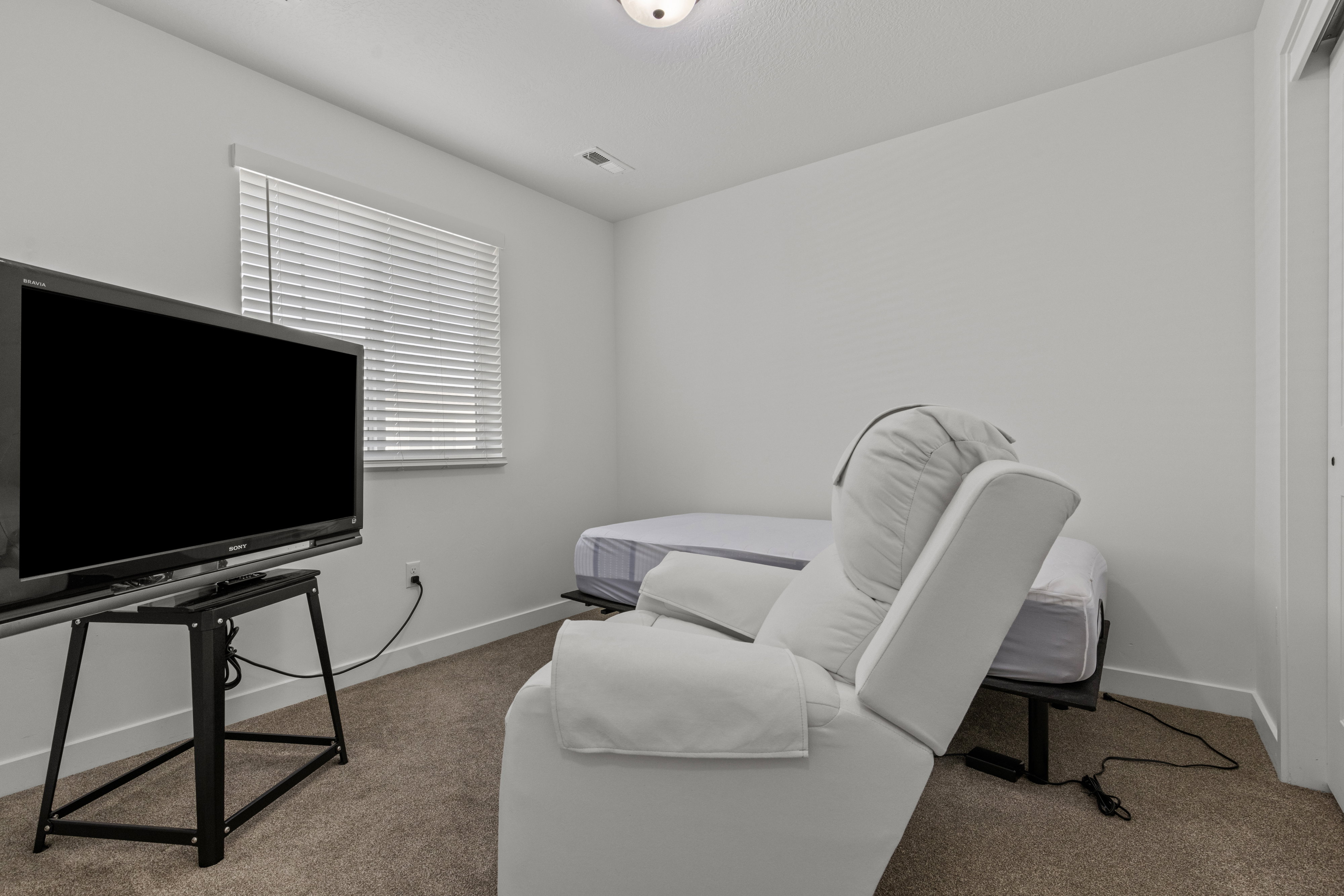 Carpeted room with a single window featuring horizontal blinds
