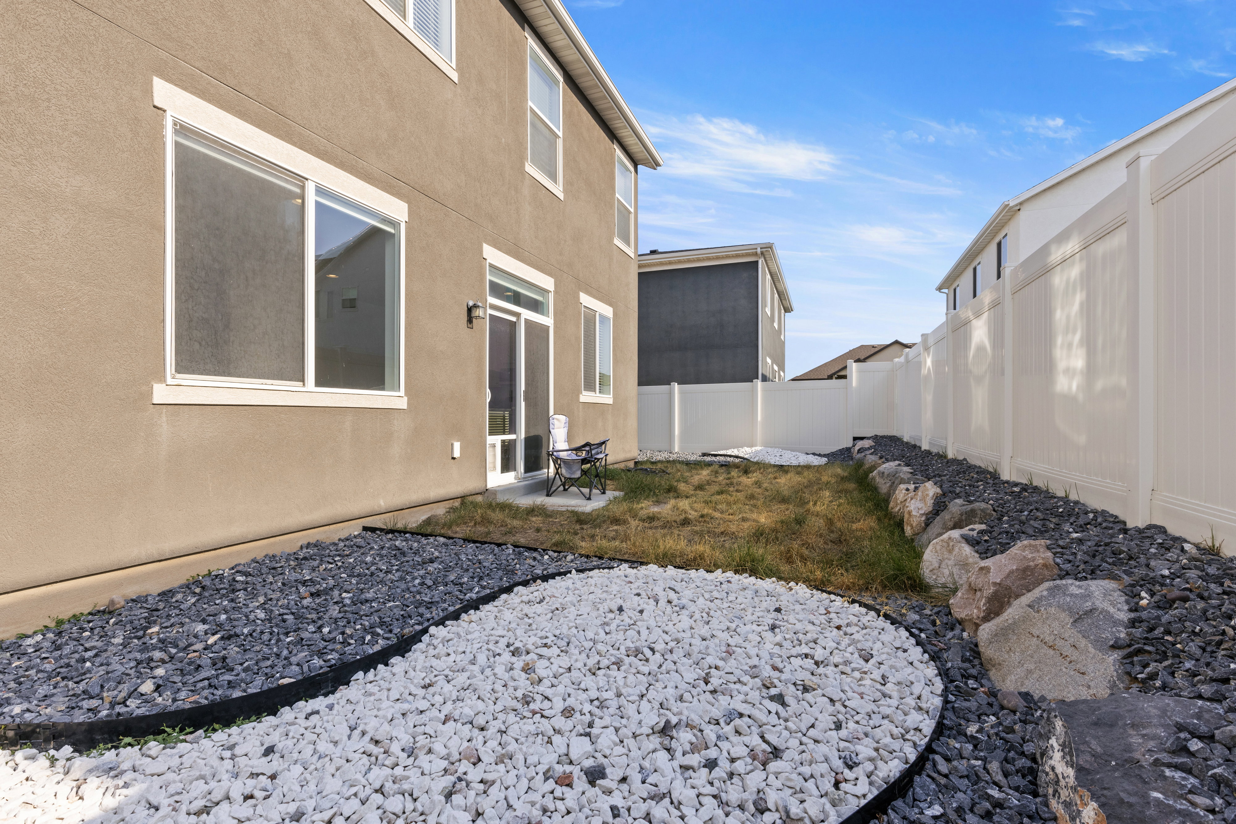 Backyard featuring a privacy fence, landscaping with decorative rocks, and a sliding glass patio door