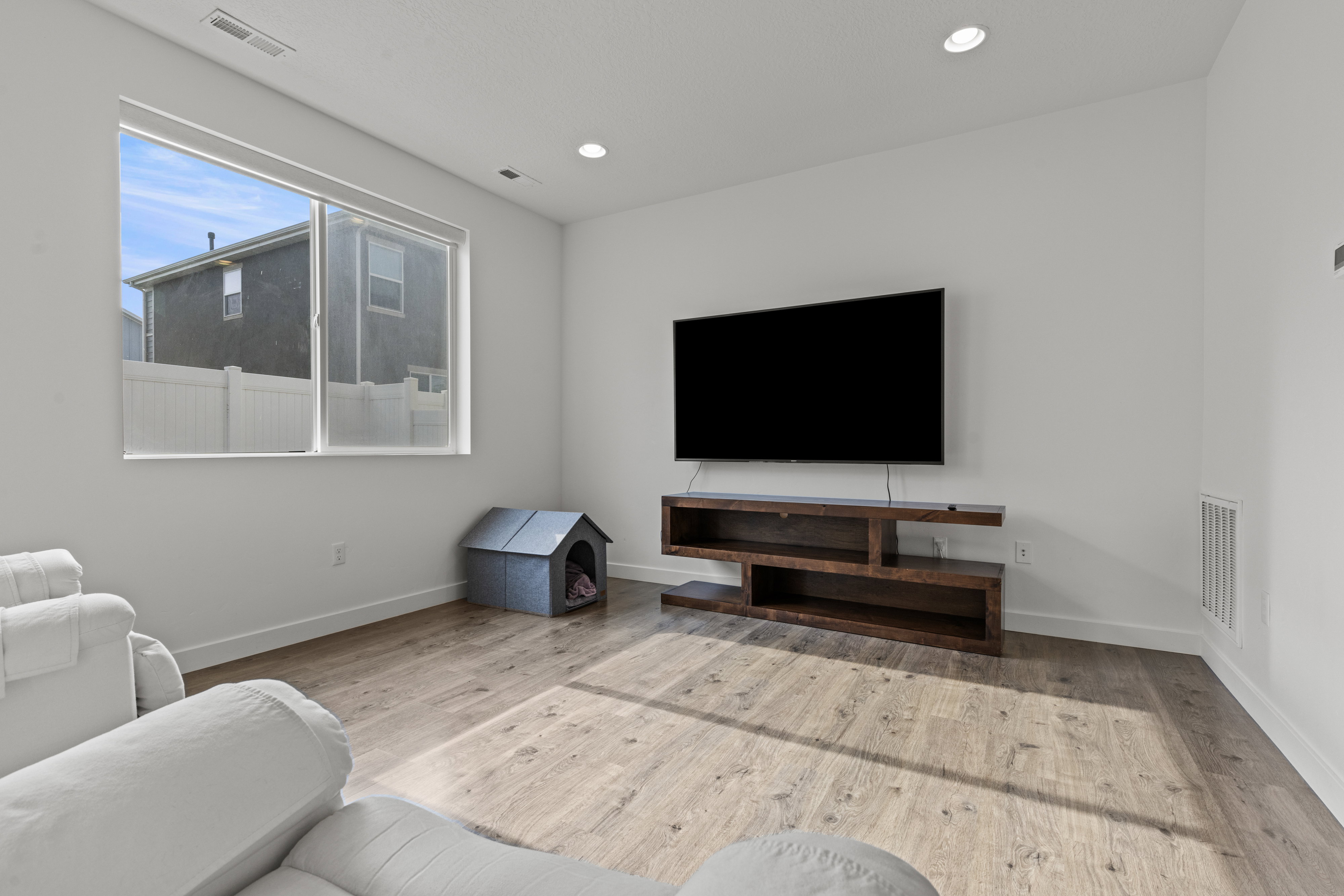 Living area with wood-finish flooring, recessed lighting, and a large window