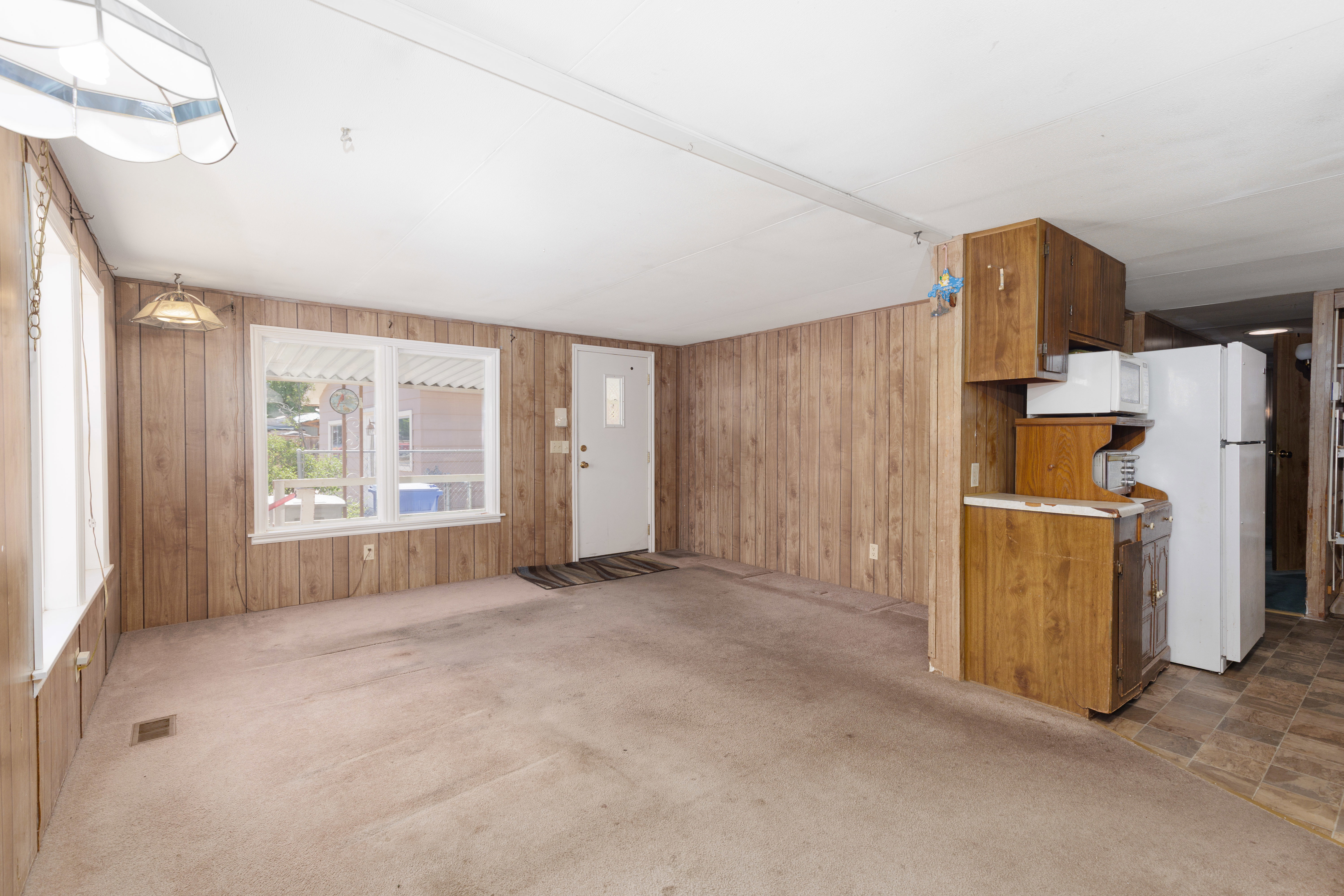 Open-concept living space featuring wood-panel walls and light-toned carpeting