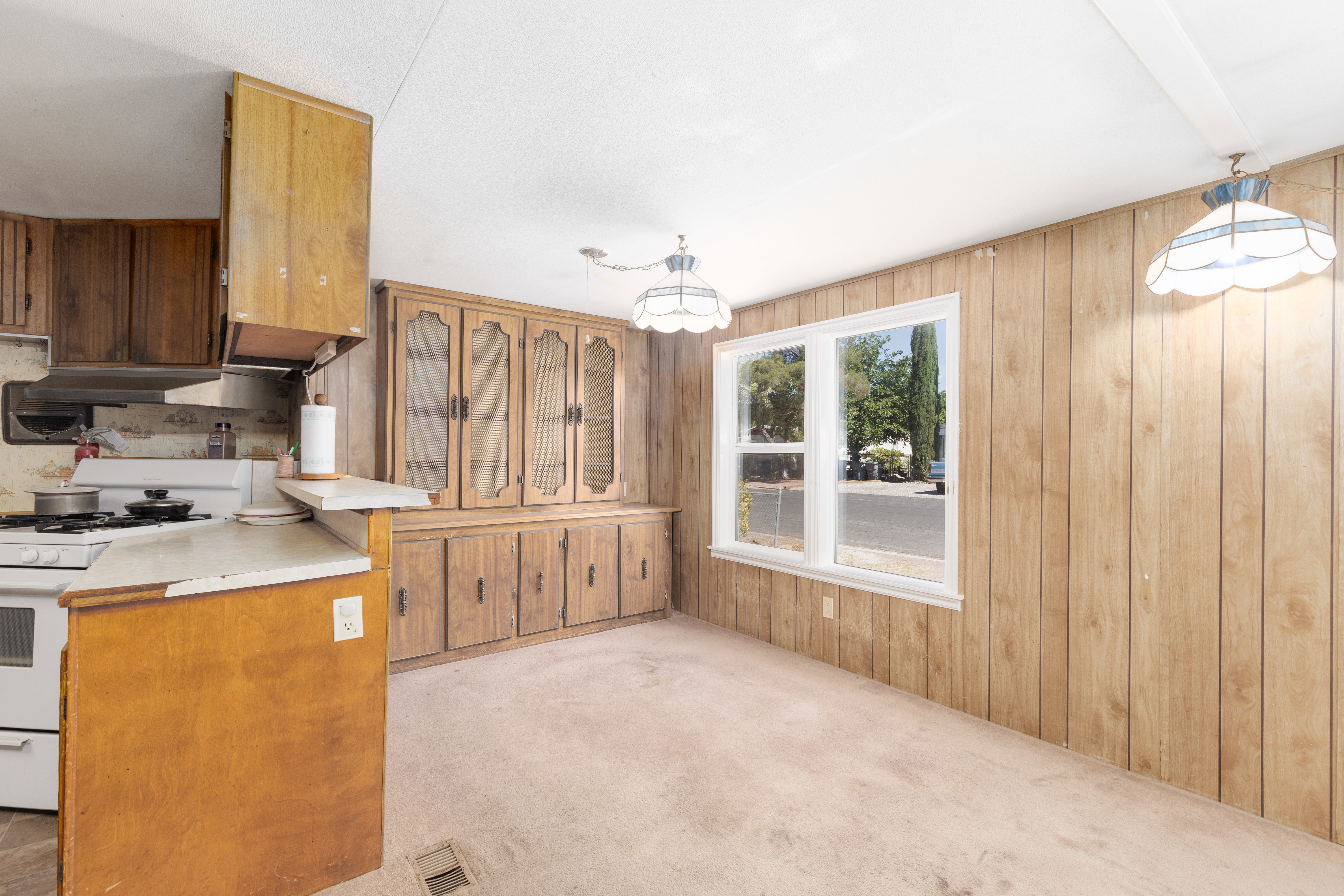 Dining area featuring wood-paneled walls and a built-in wooden hutch with glass-fronted upper cabinetry