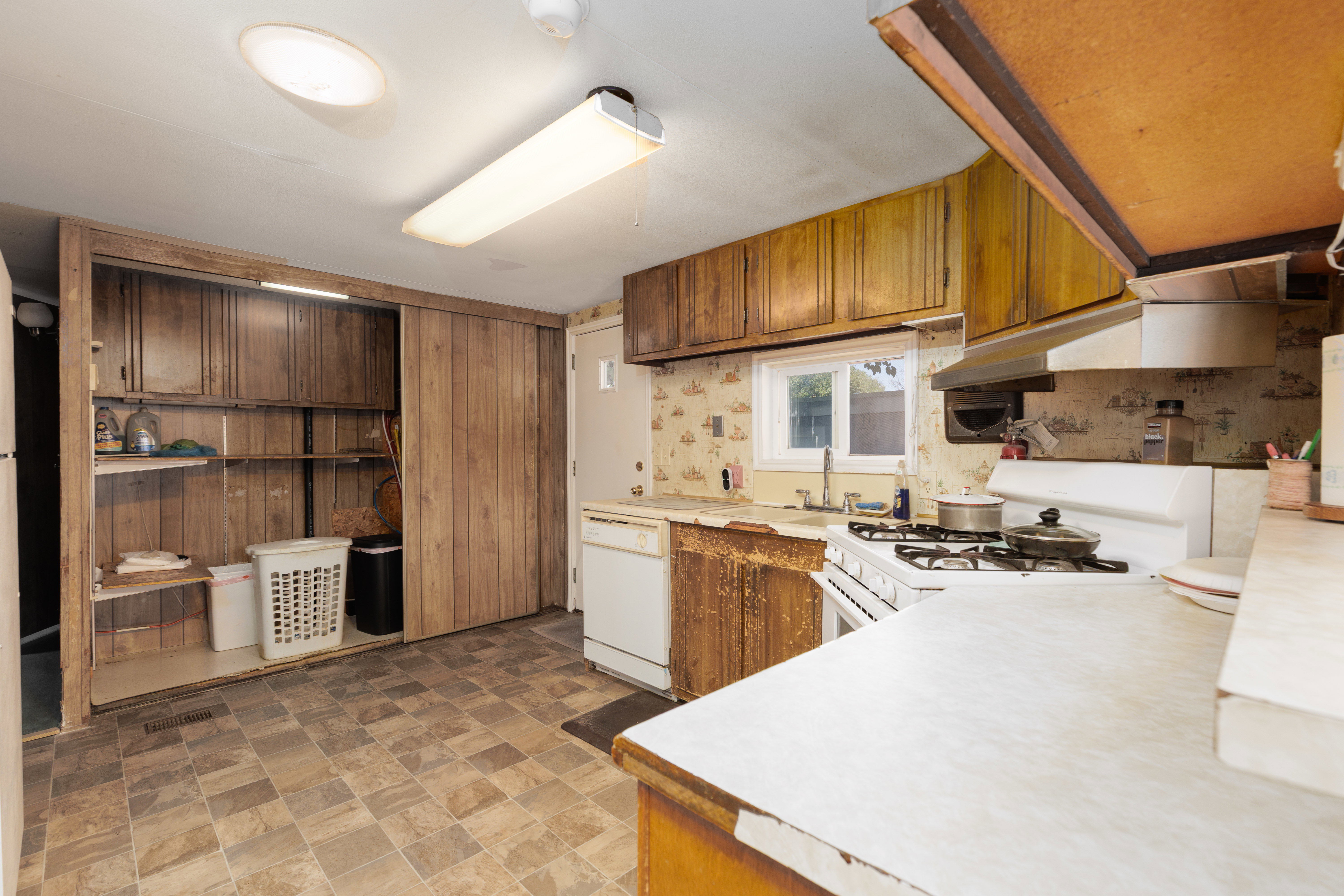Kitchen featuring a gas range, white dishwasher, and wall-mounted cabinetry