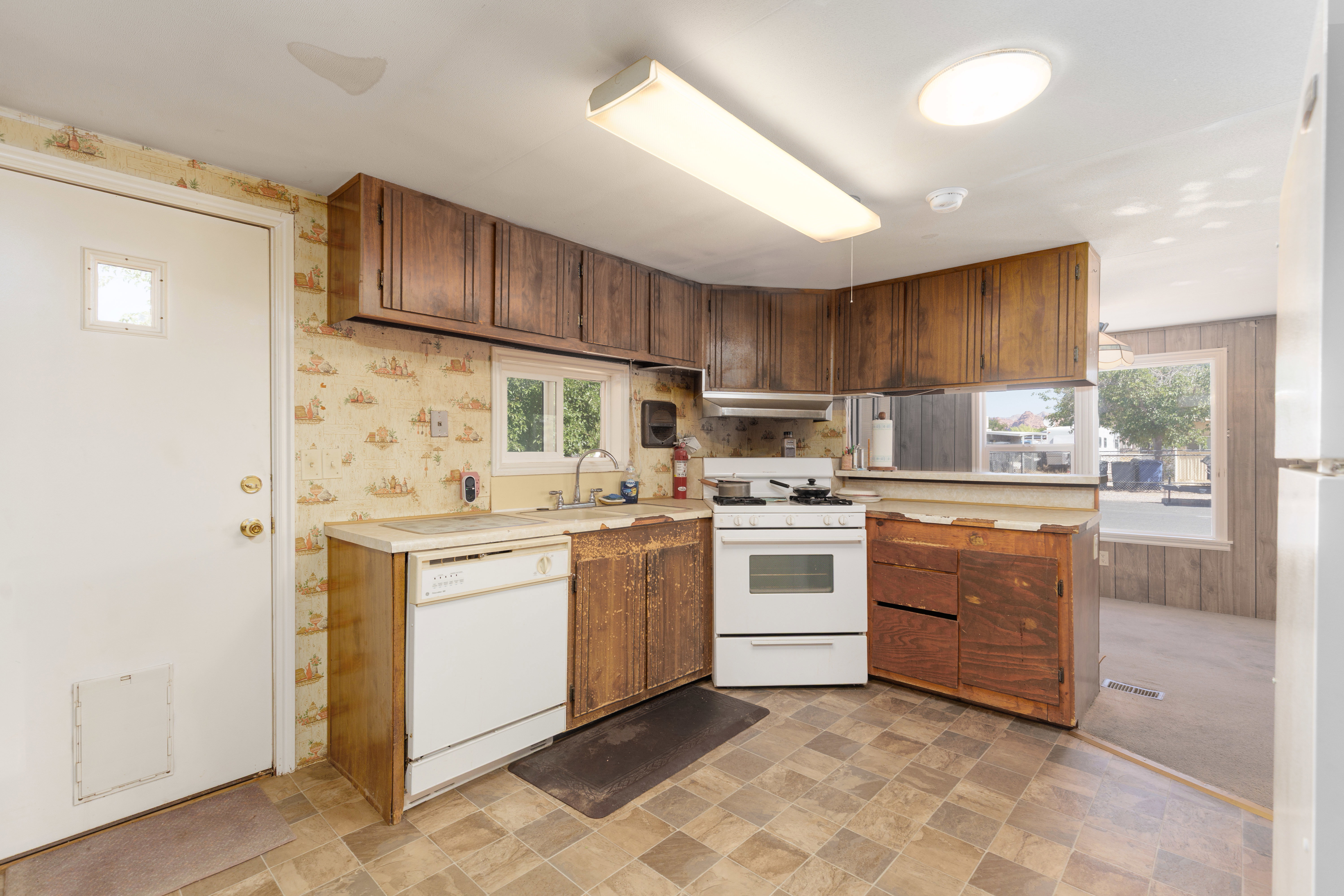 Kitchen featuring wood-finish cabinetry, a white dishwasher, and a white oven/range