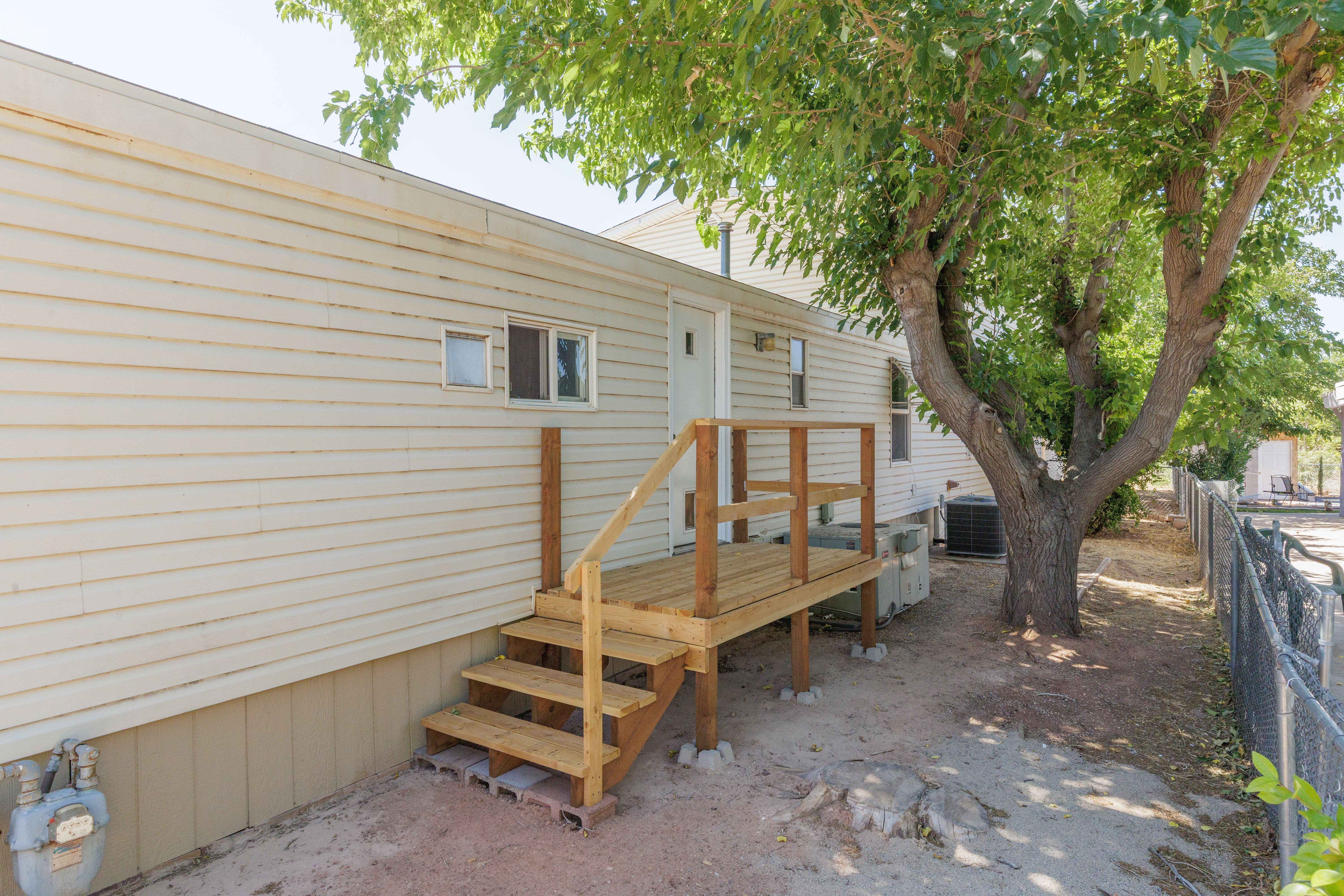Exterior featuring a wood deck with stairs and railing, vinyl siding, and a mature shade tree