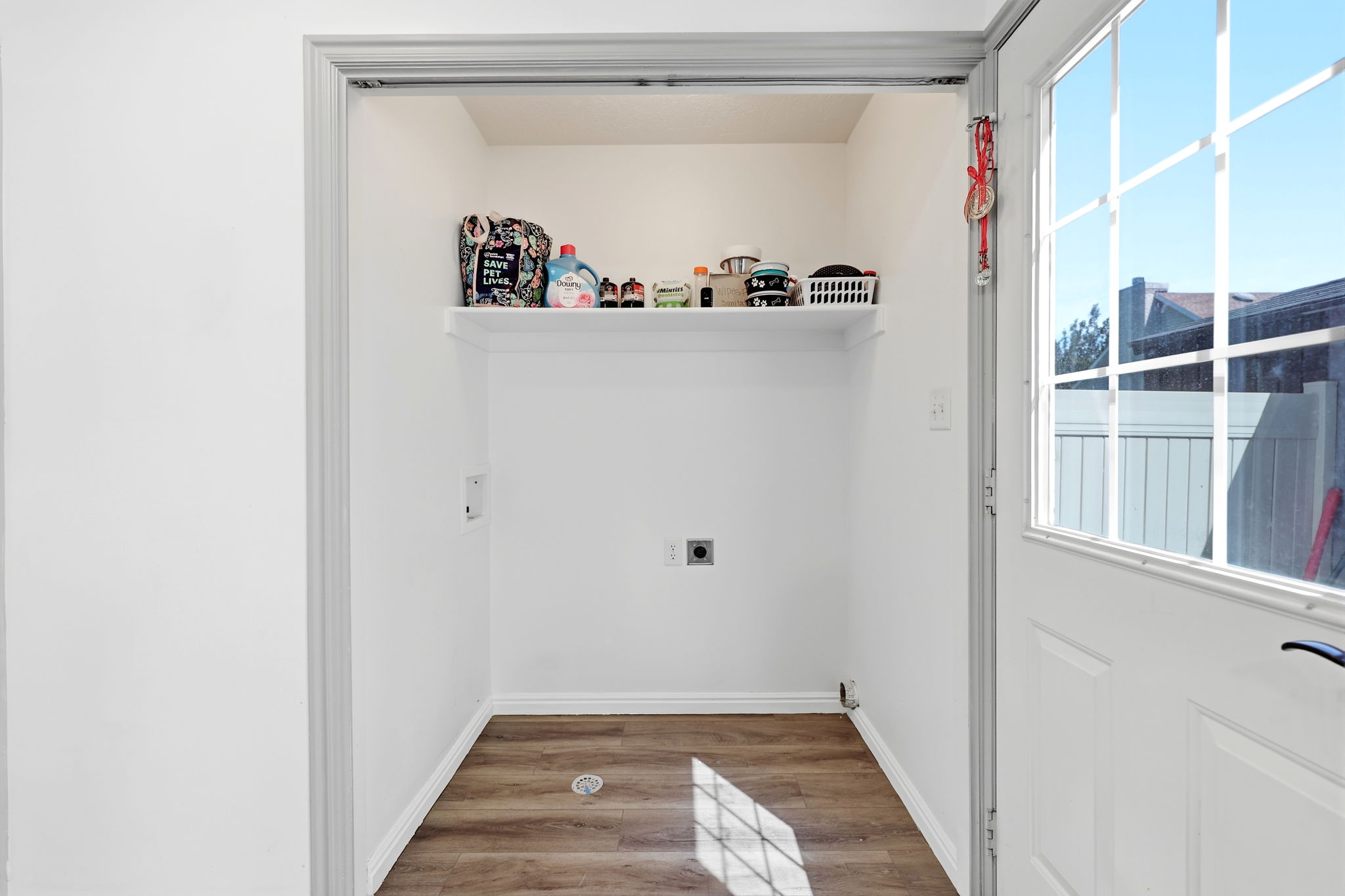 Dedicated laundry area featuring a built-in shelf, plumbing hookups, electrical outlet, and wood-finish flooring