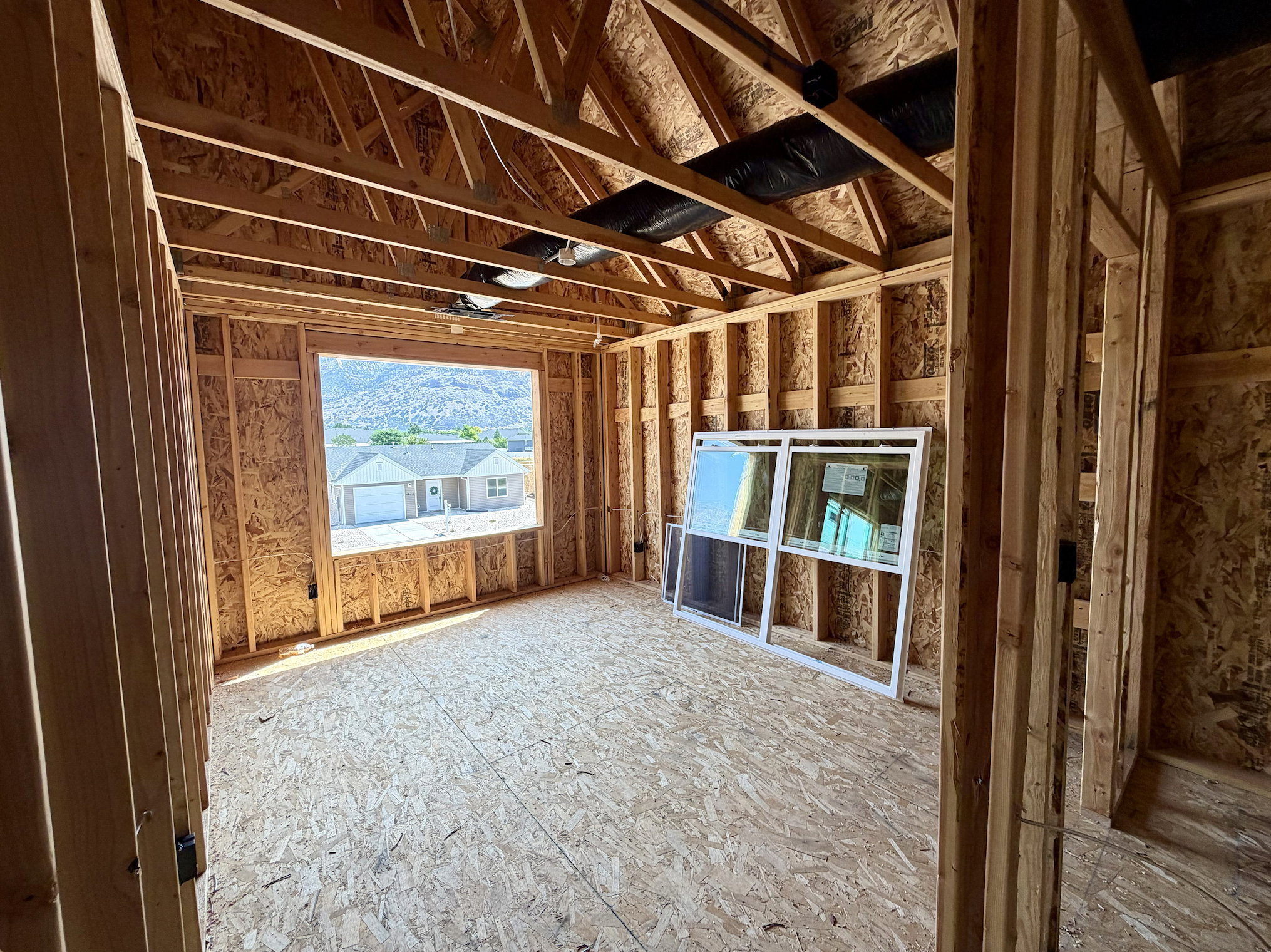 Framed interior room with visible structural elements and engineered wood subflooring