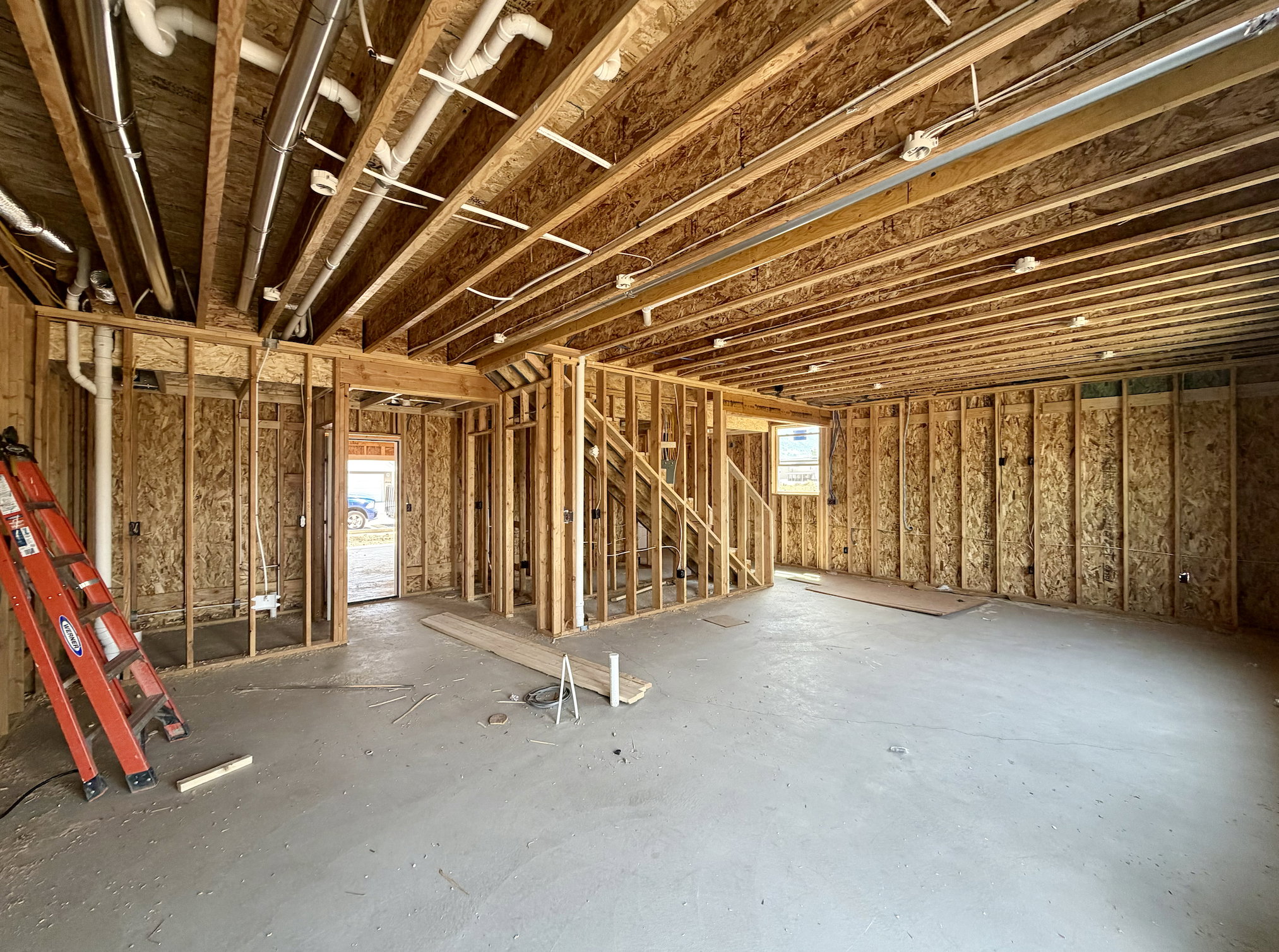Framed interior space featuring exposed joists, subflooring, and a concrete floor