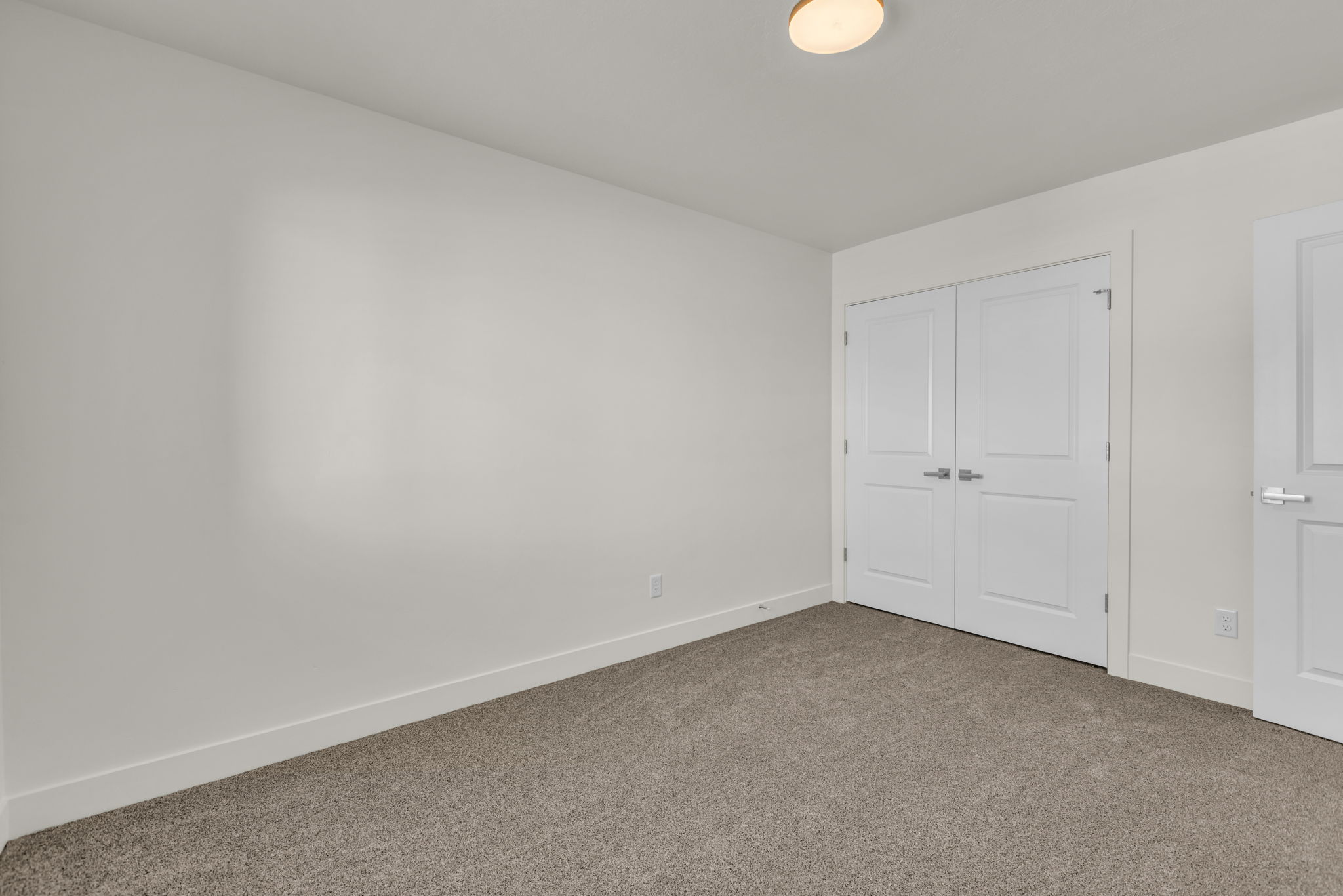 Neutral toned room with wall-to-wall carpeting and white baseboards