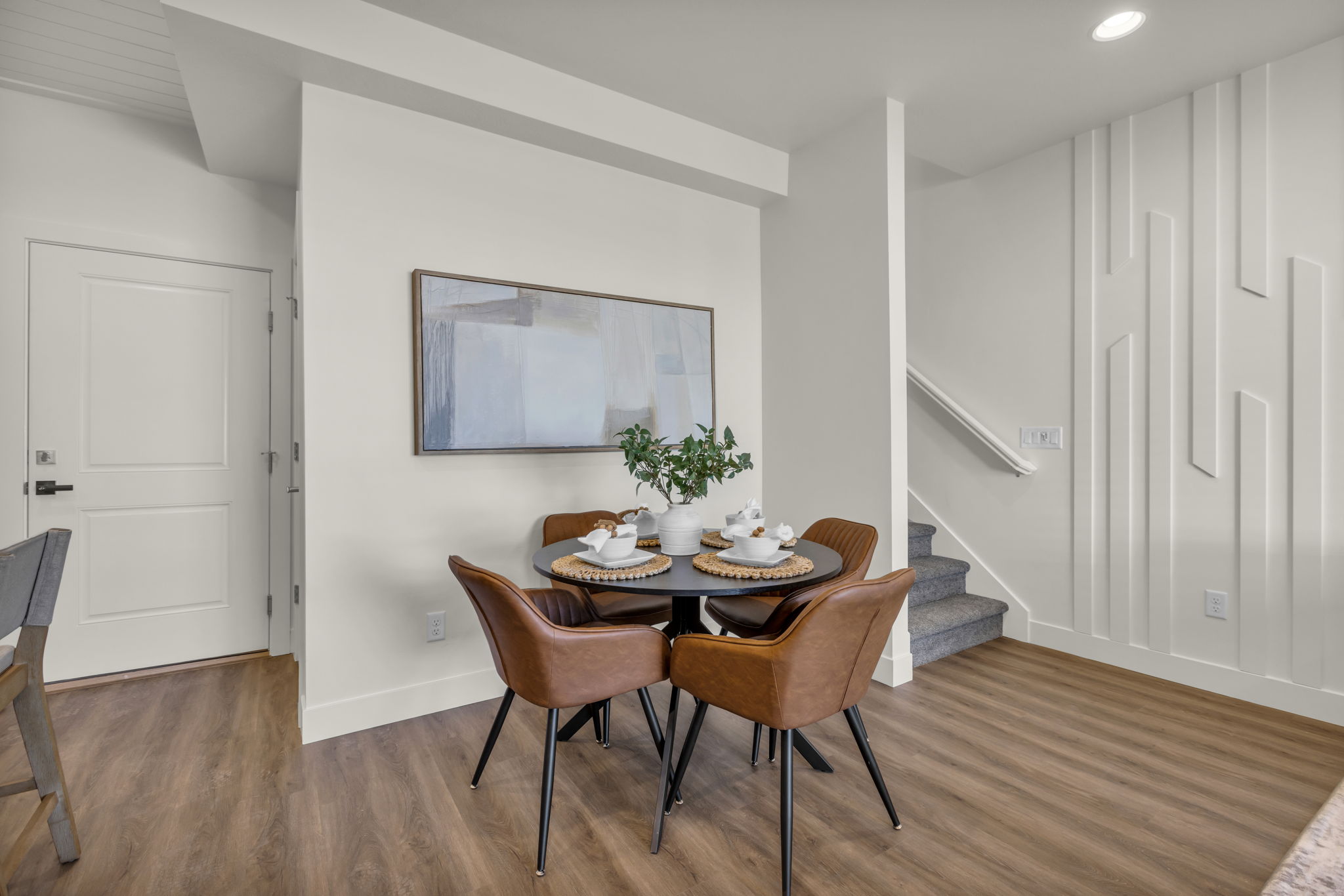 Open-concept dining area featuring wood-finish flooring, a contemporary accent wall, recessed lighting, and a neutral color palette