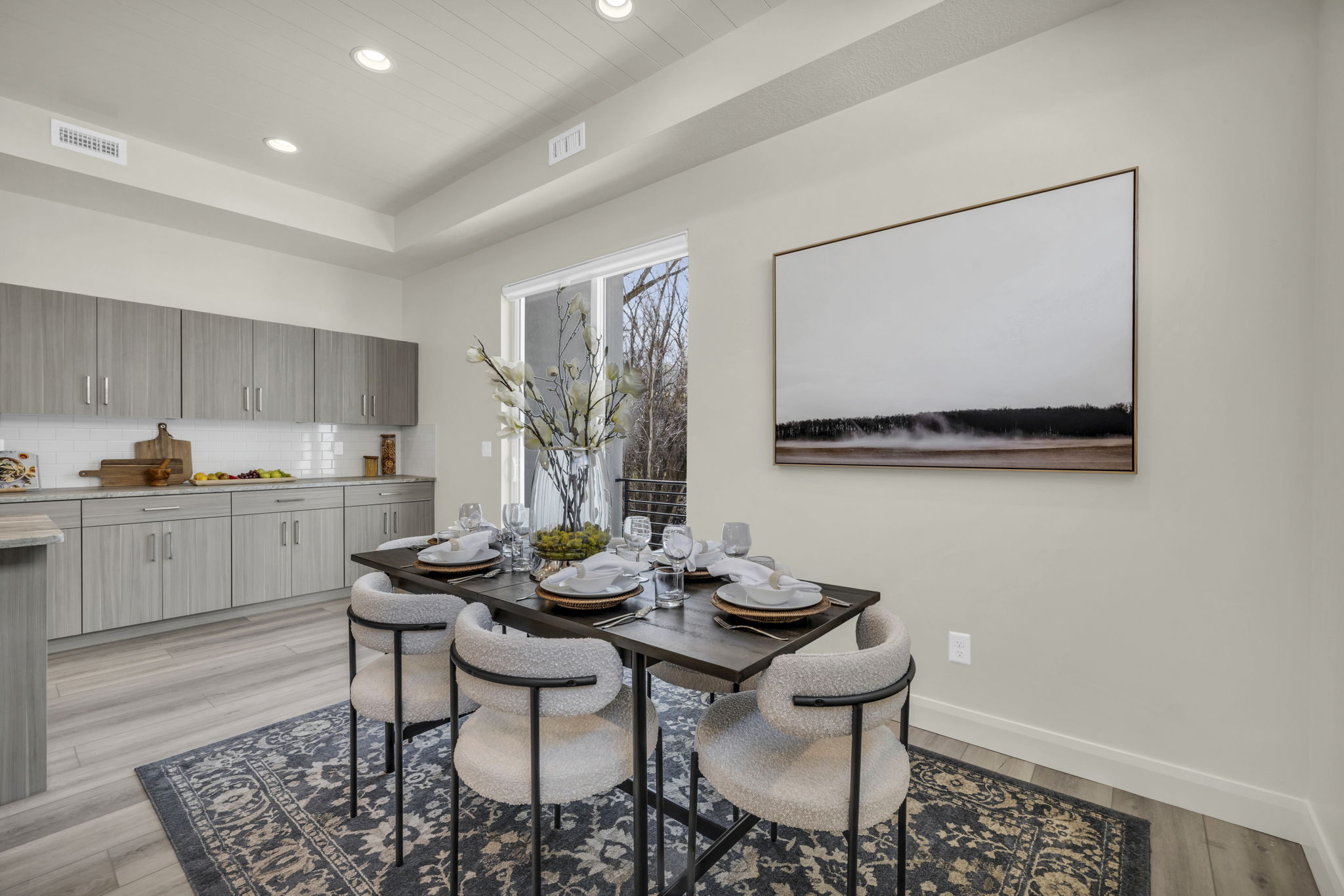 Open-concept dining area featuring wood-finish flooring, a tray ceiling with recessed lighting, and a sliding glass door
