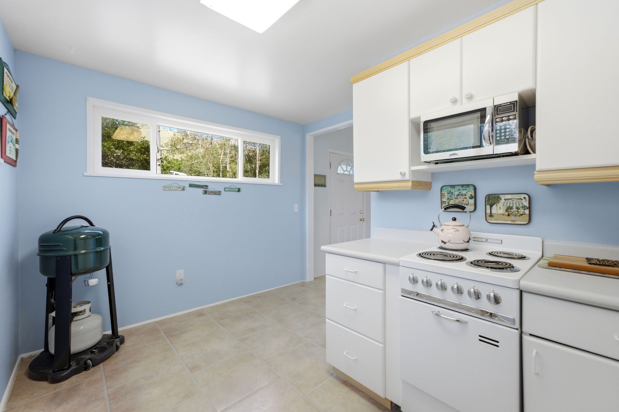 Kitchen featuring white cabinetry, white countertops, a built-in microwave, and a white oven/range