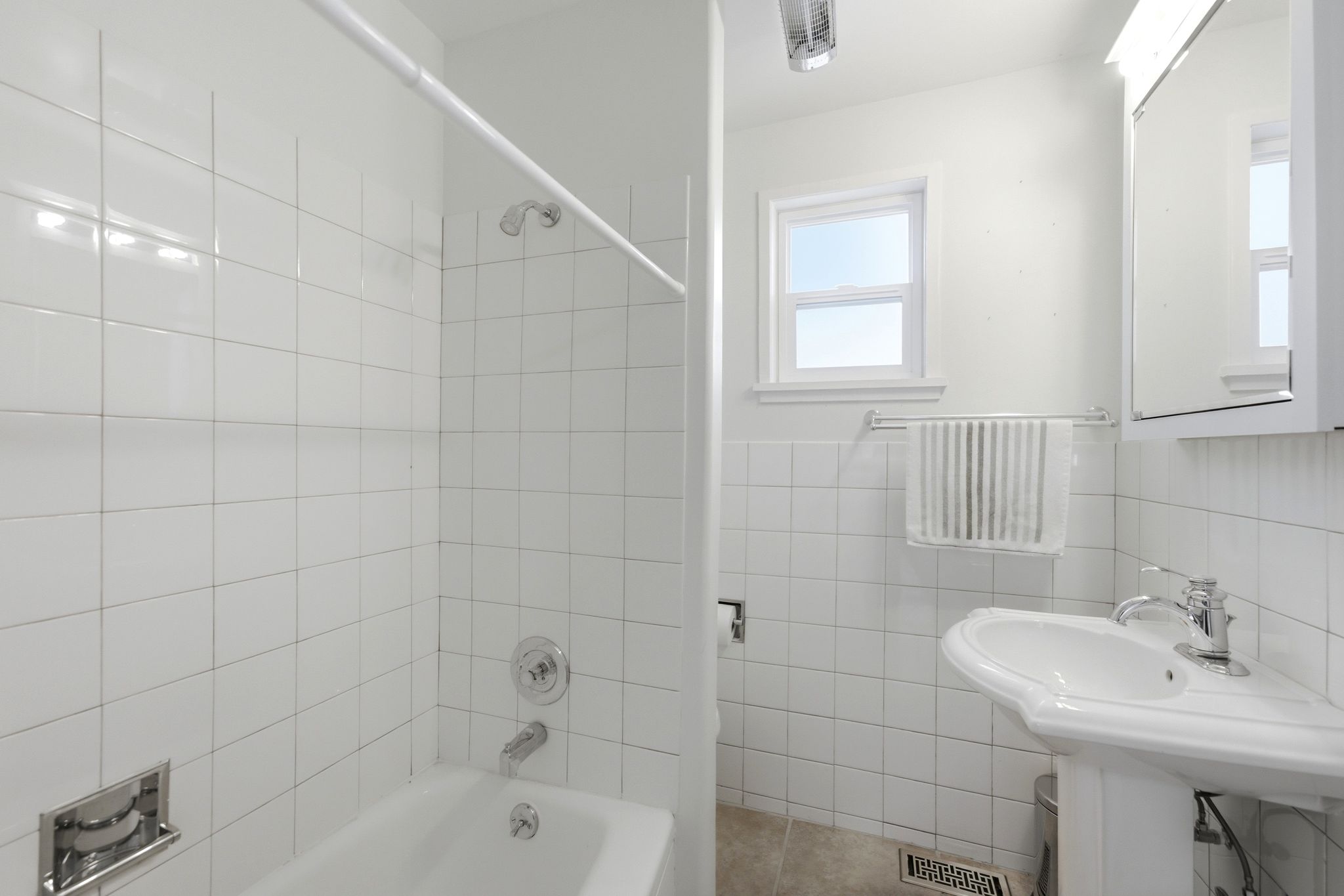 Bathroom featuring a pedestal sink with chrome fixtures, a mirrored medicine cabinet, and a window for natural light