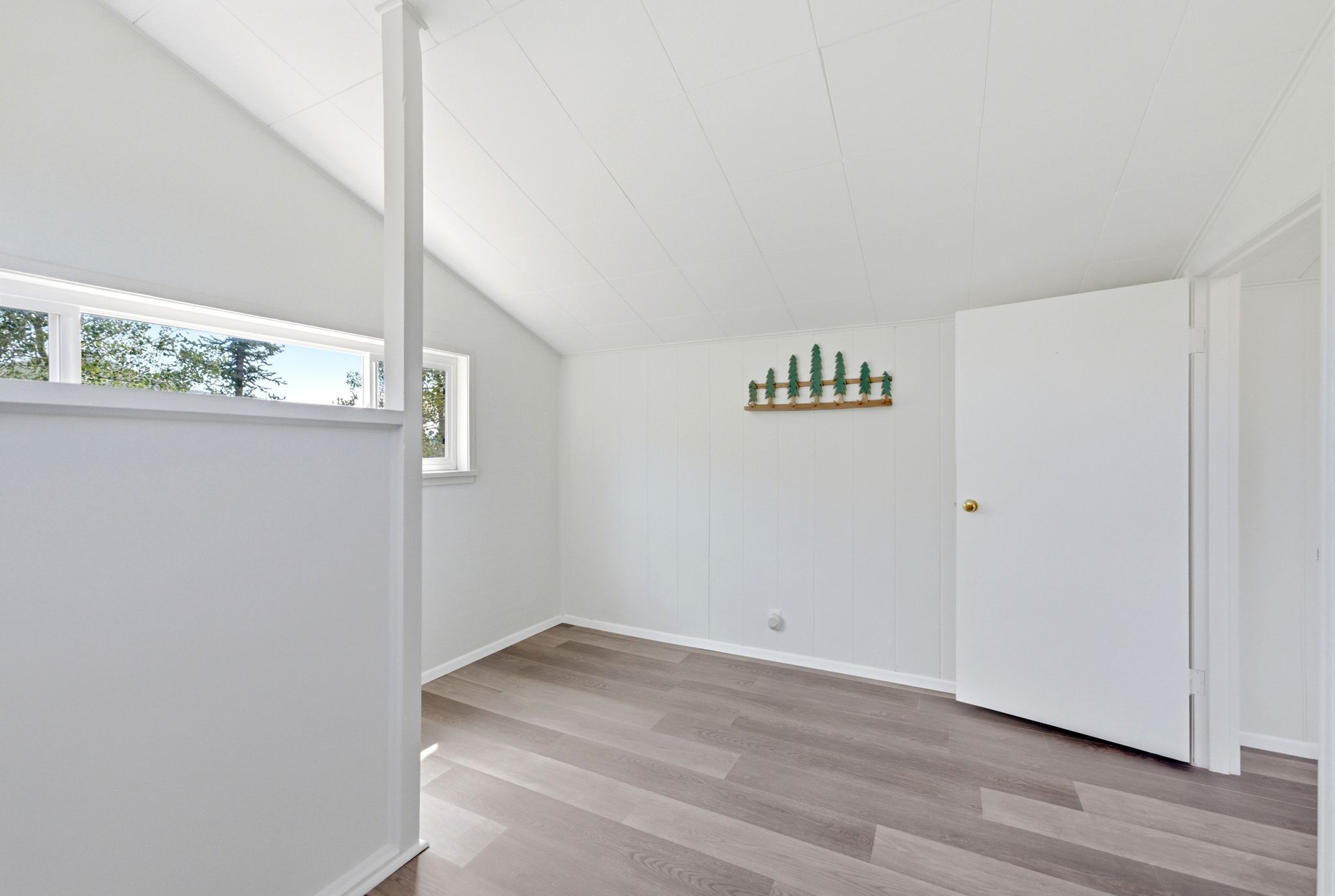 Room featuring wood-finish flooring, vaulted ceiling, and multiple windows