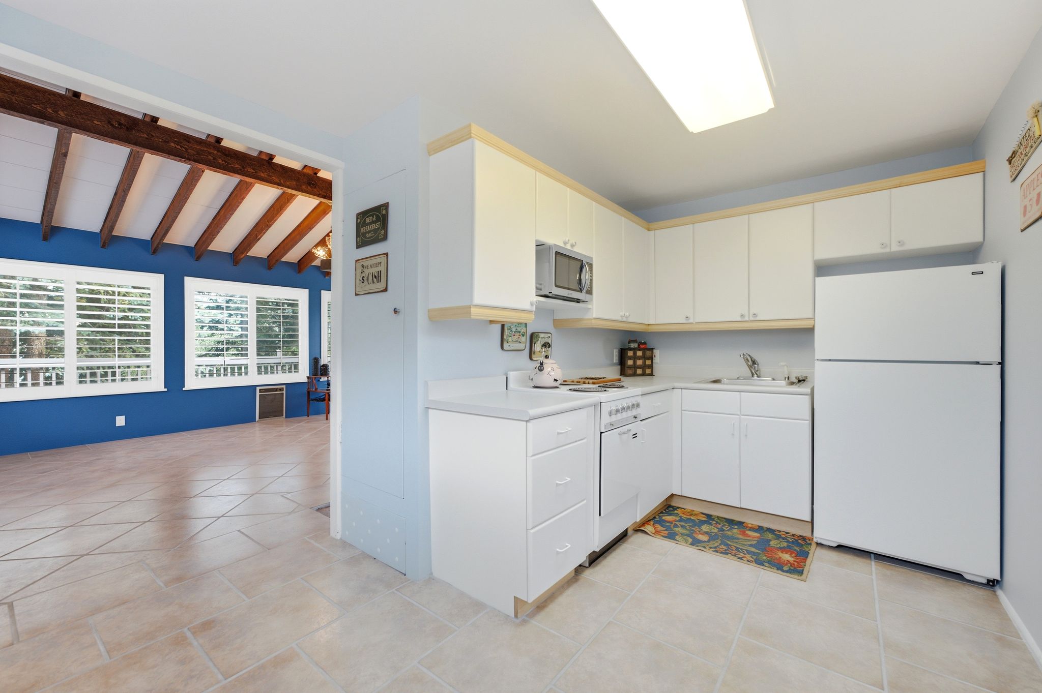L-shaped kitchen featuring white cabinetry, light countertops, and integrated appliances