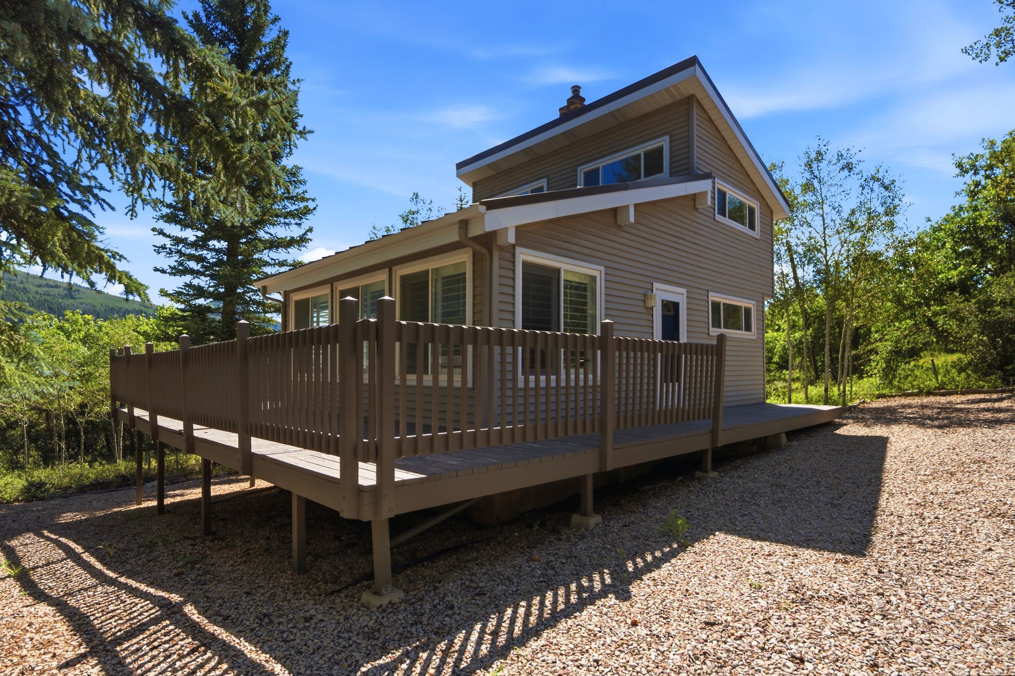 Elevated wood-finish deck surrounding a two-story residence with horizontal siding