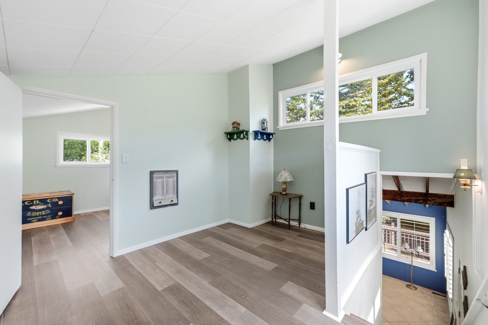 Interior space featuring wood-finish flooring, light green wall paint, and multiple windows