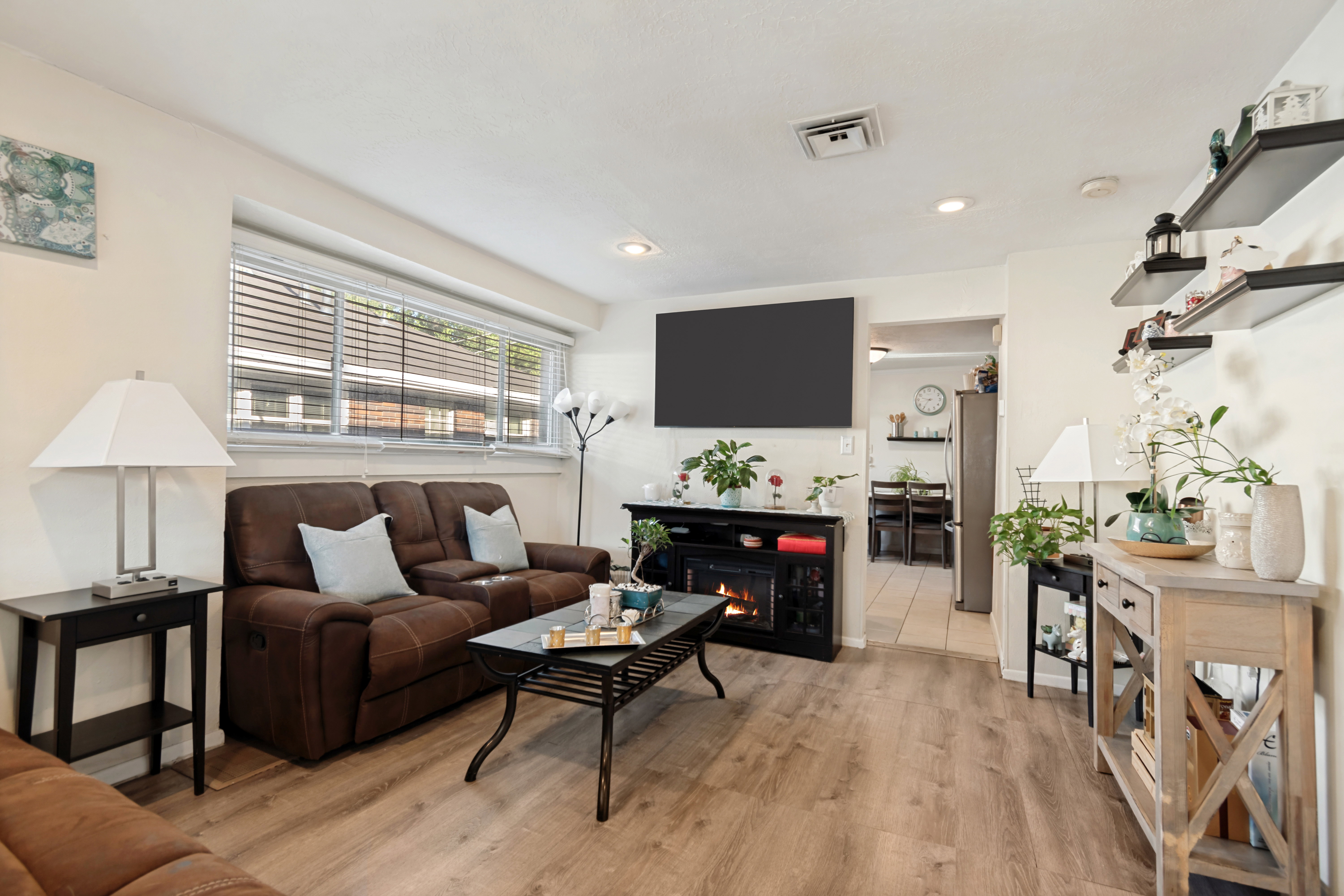 Living area featuring light wood-finish flooring, recessed lighting, and a large window with horizontal blinds