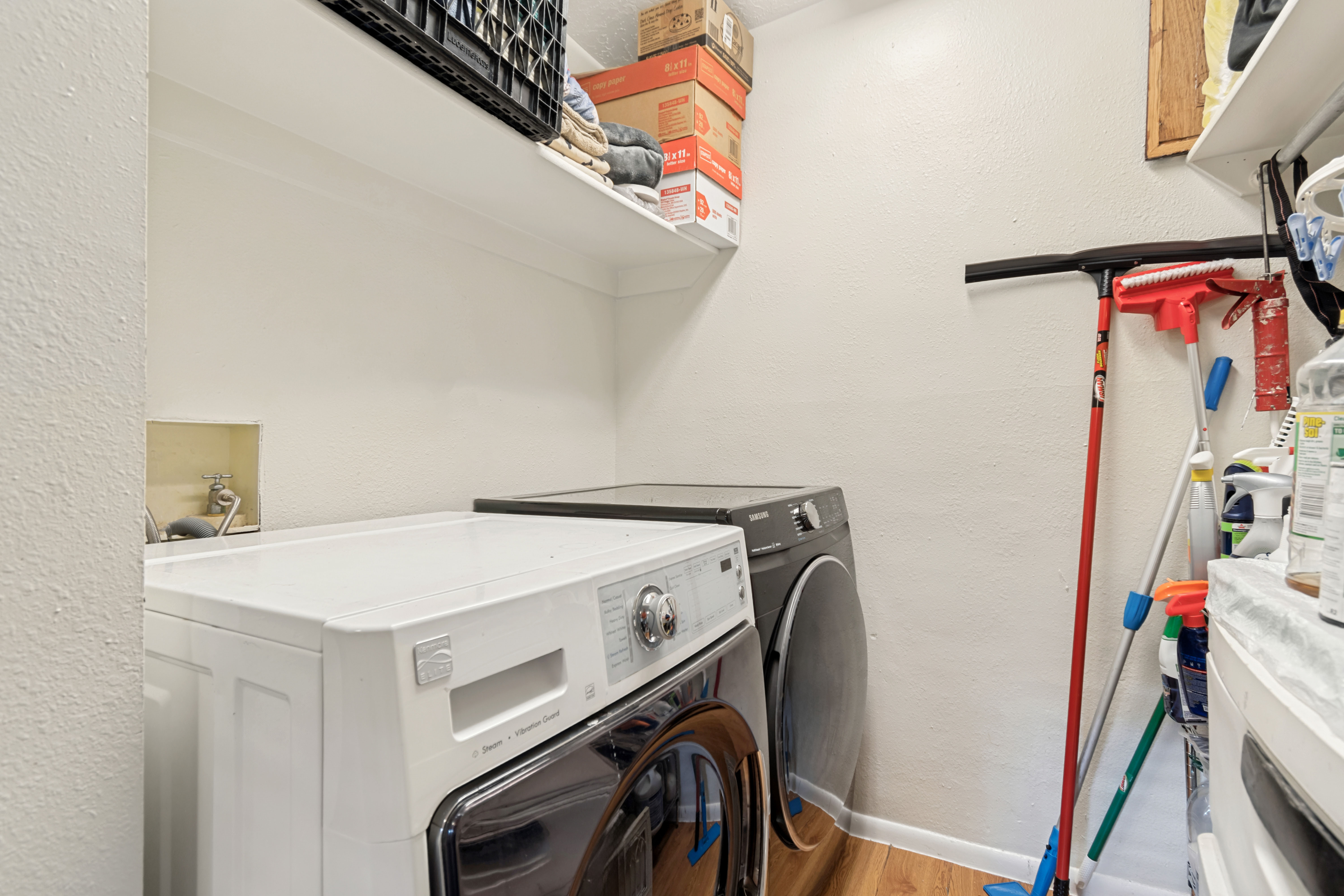 Dedicated laundry space featuring a white top shelf, wood-finish flooring, and light-toned walls