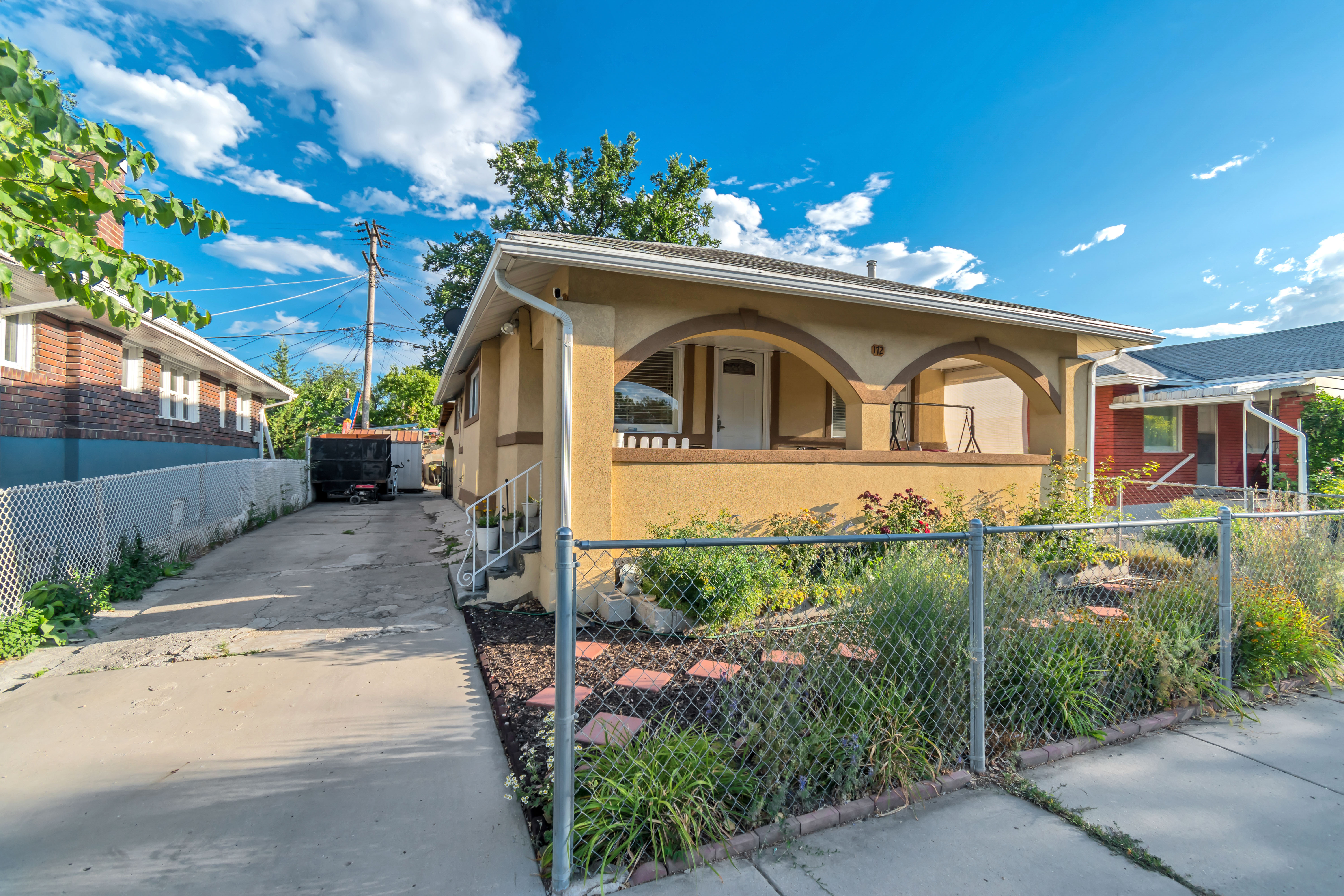 Stucco exterior with arched porch entry, concrete driveway, and front garden area