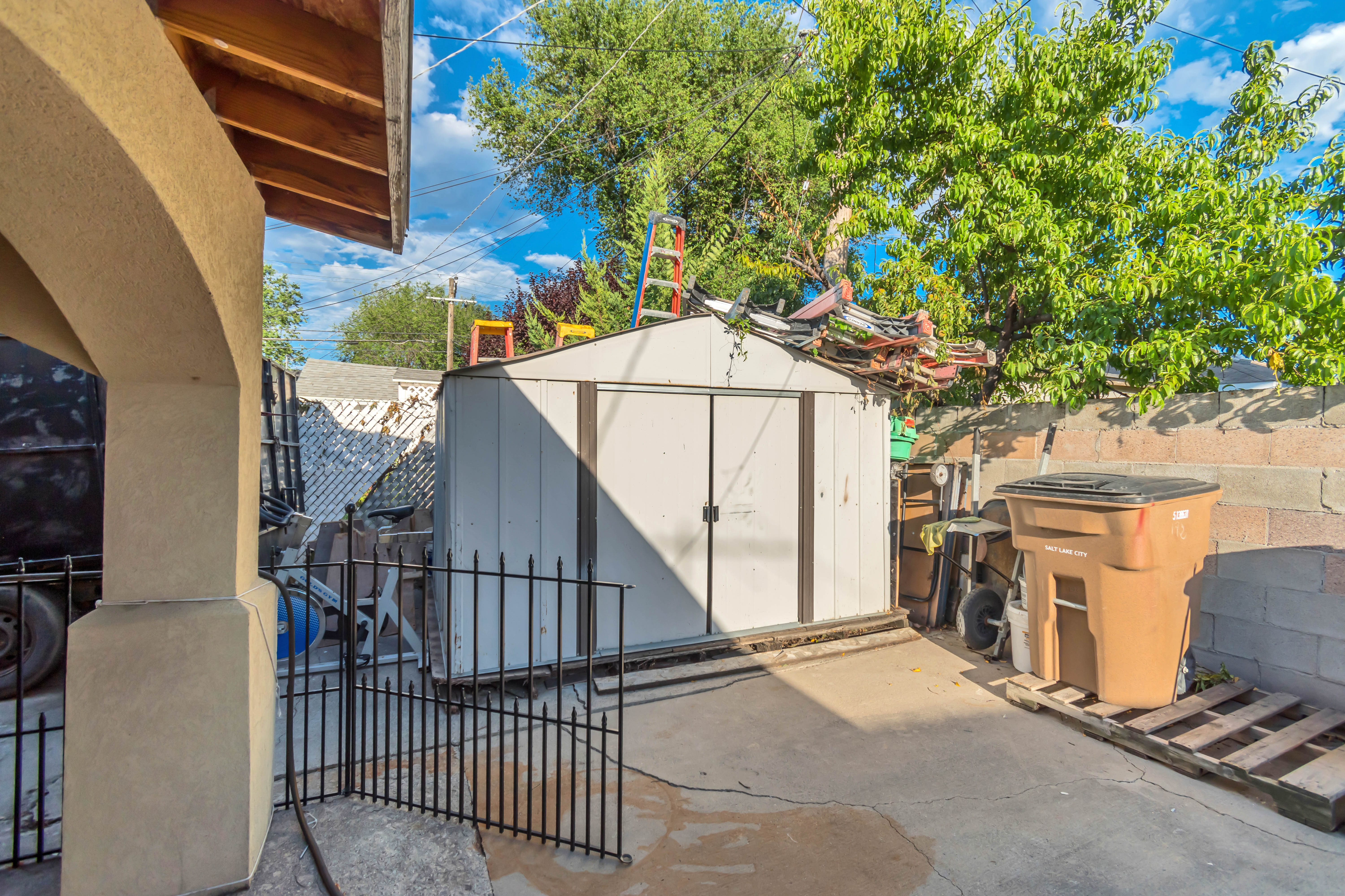 Detached storage shed featuring double doors and an adjacent concrete patio area