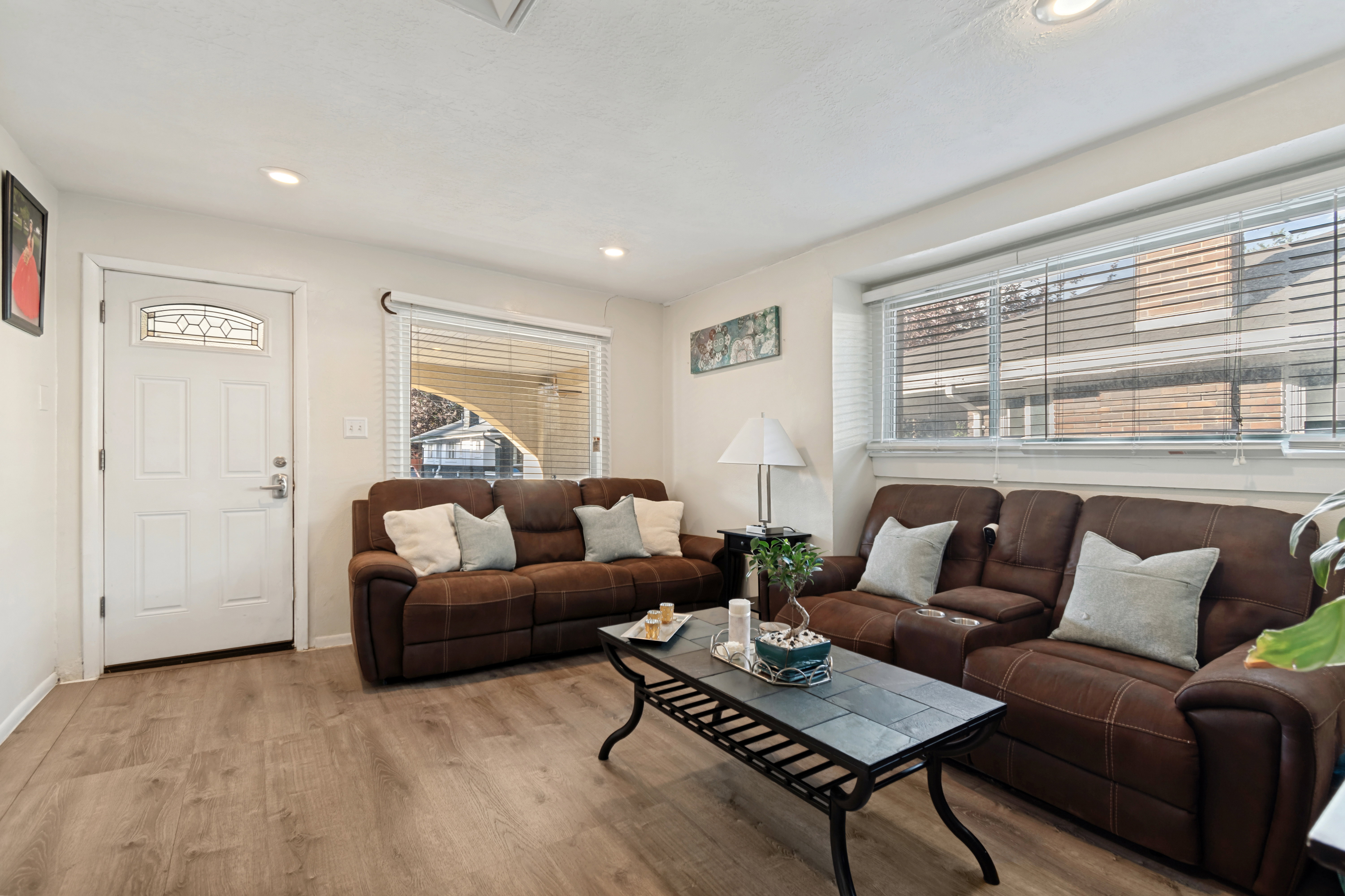 Living area featuring wood-finish flooring, recessed lighting, and a white entry door with decorative glass inserts