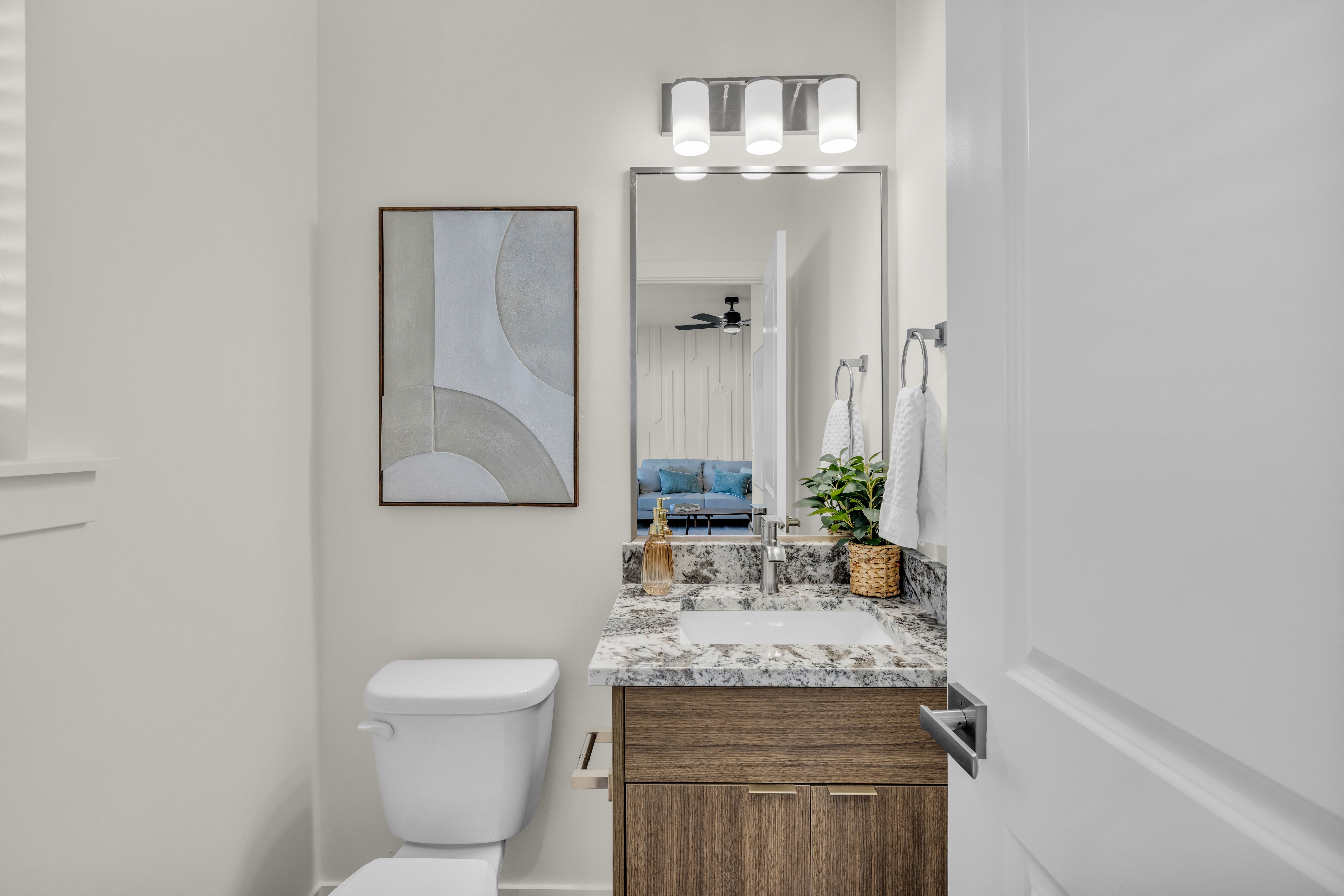 Modern bathroom vanity featuring a granite countertop with an integrated sink, wood-finish cabinetry, and a chrome faucet