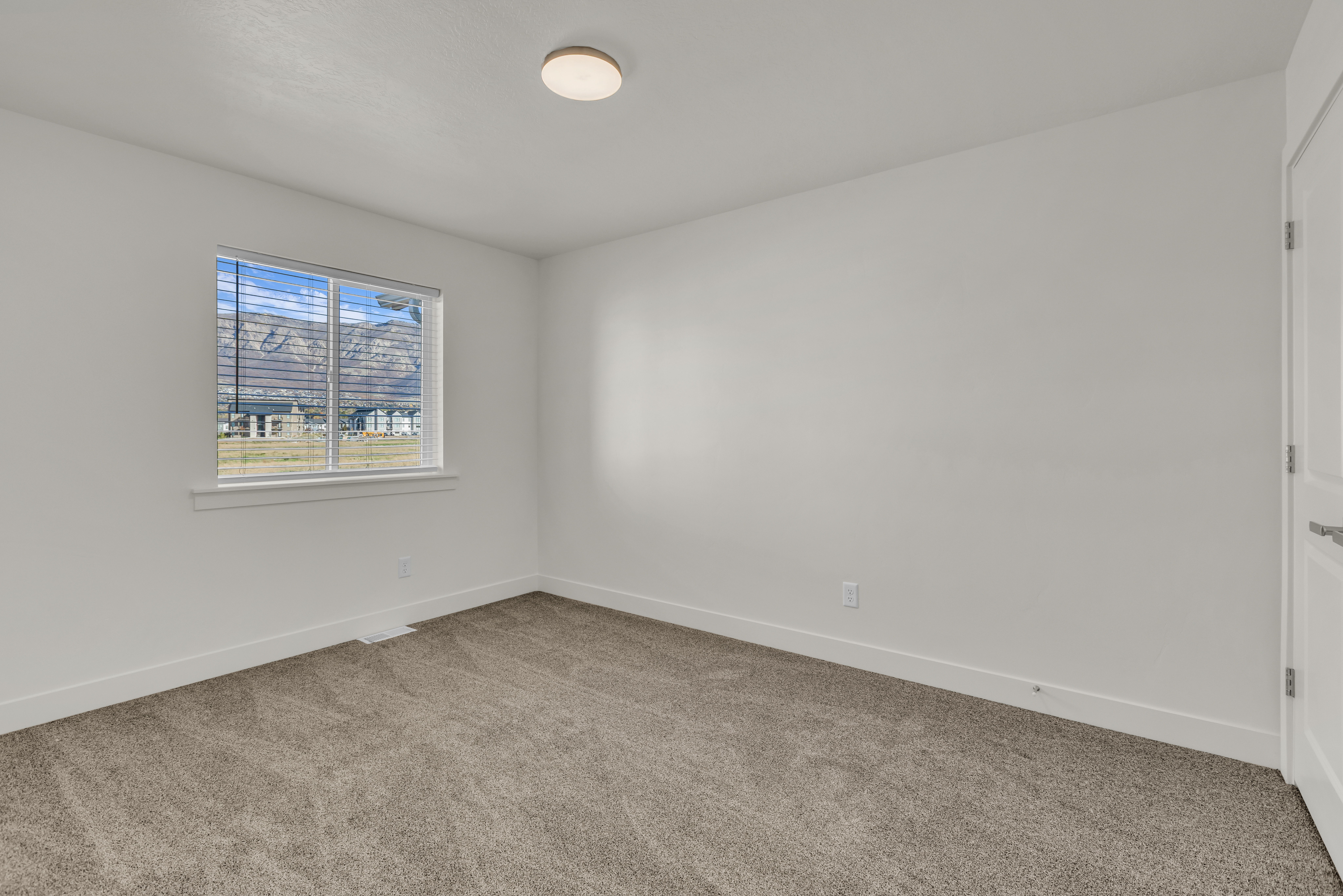 Spacious room featuring neutral paint, gray carpet, and a window with white blinds