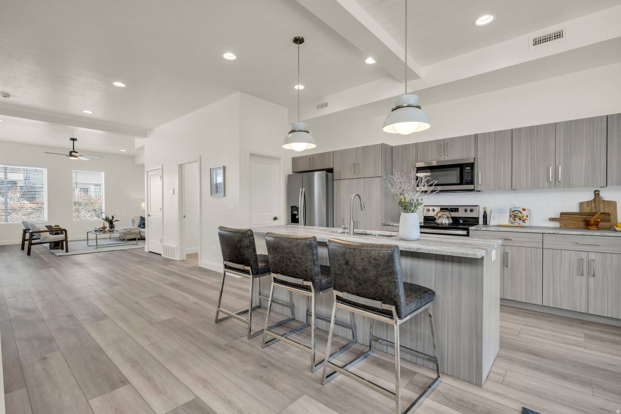 Open-concept kitchen featuring an island with seating, stainless steel appliances, wood-finish cabinetry, and recessed lighting