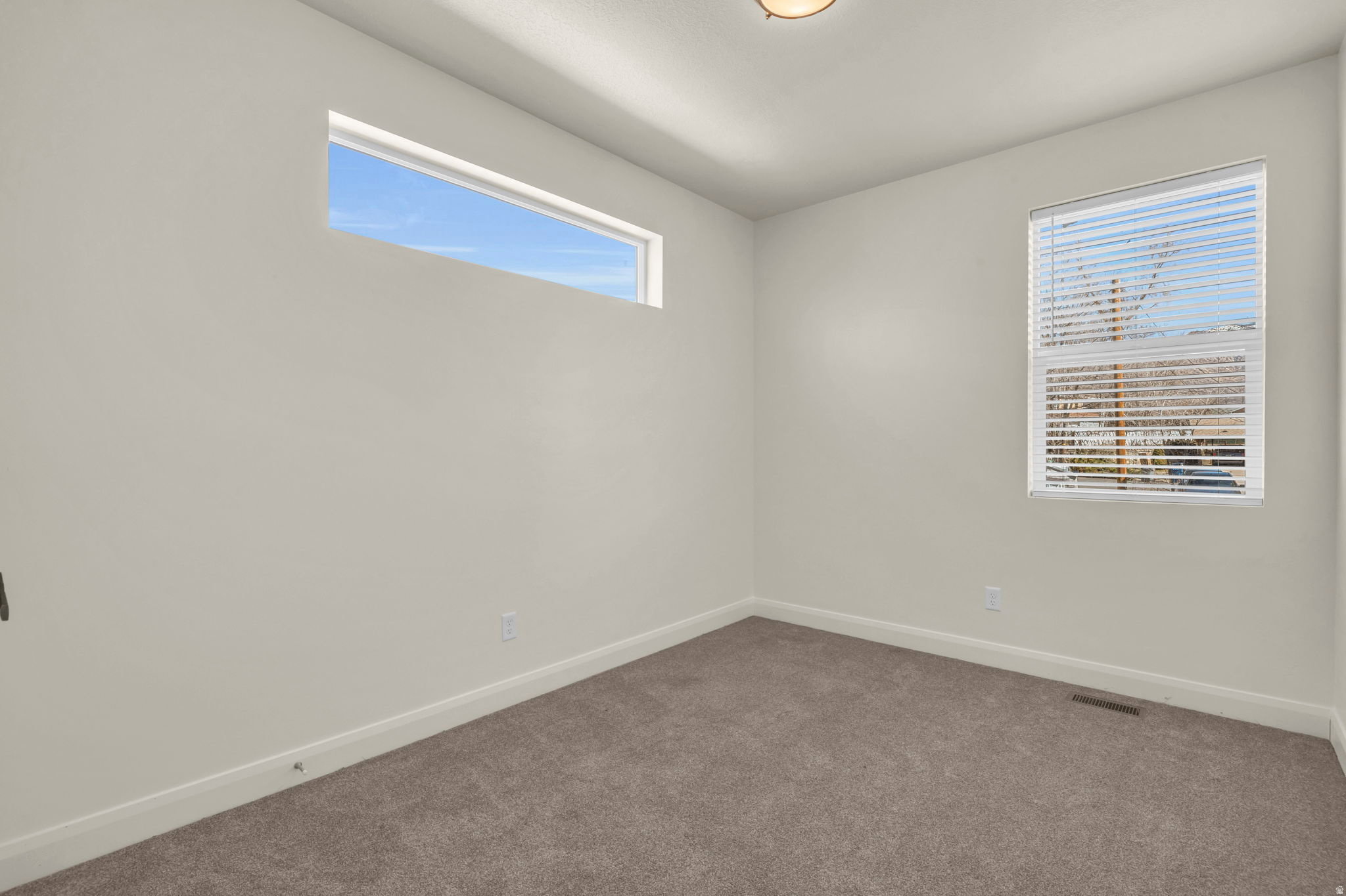 Spacious room featuring neutral carpeting and light-toned walls