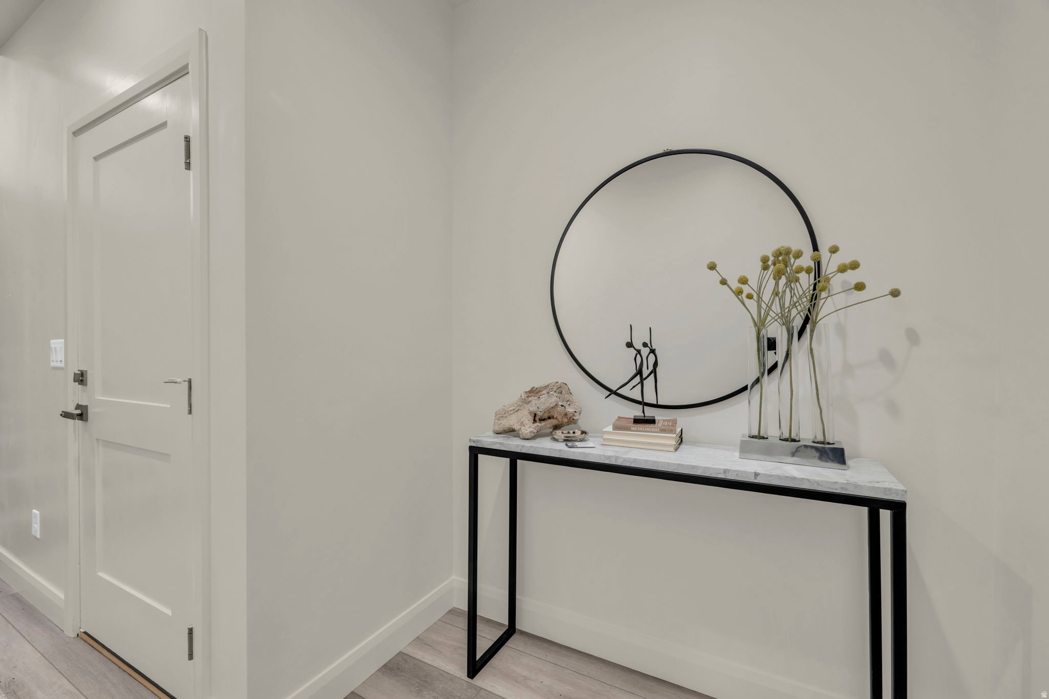 Crisp white walls with streamlined baseboards, wood-finish flooring, and a modern two-panel interior door with matte black hardware