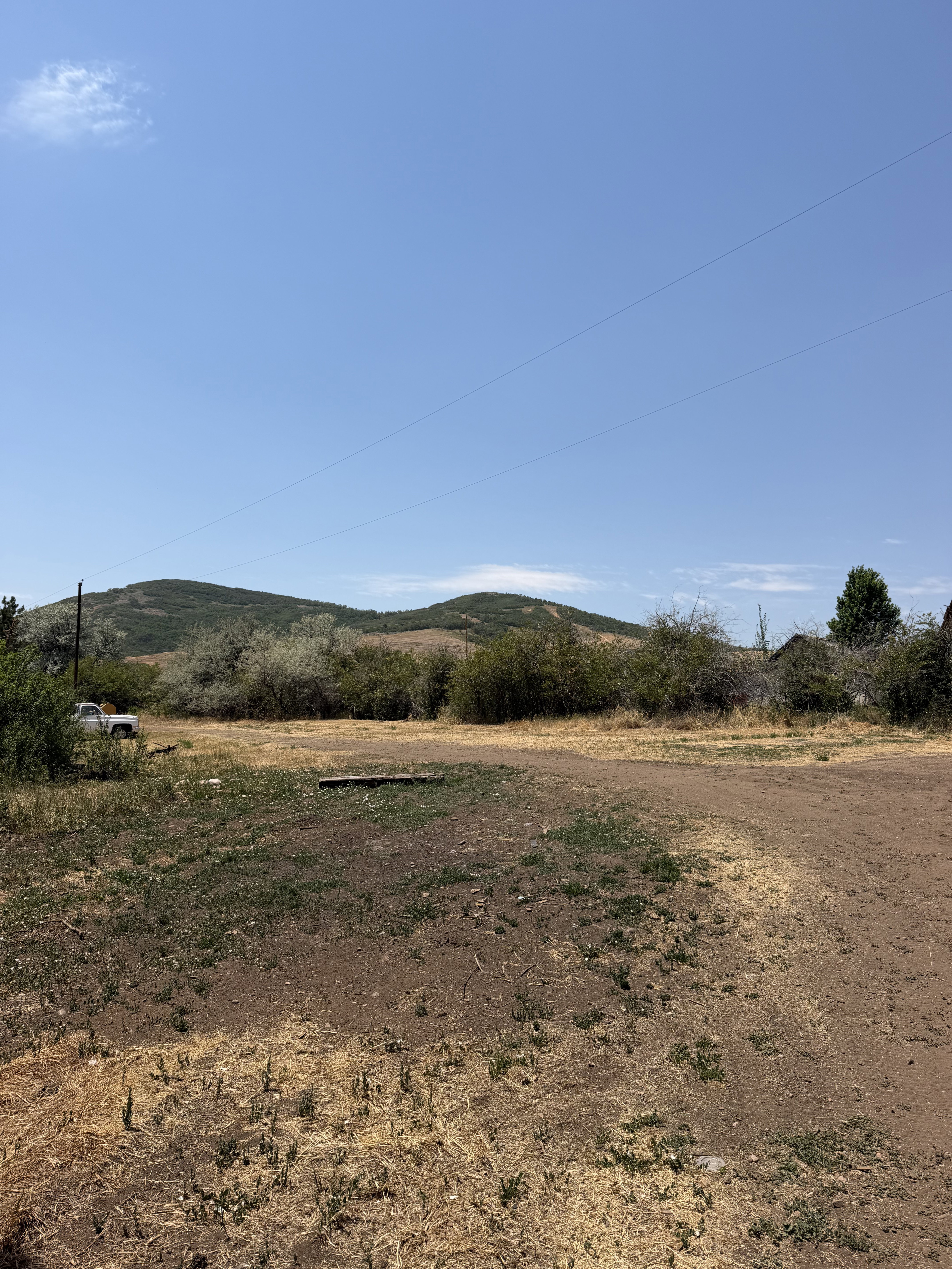Expansive lot featuring a dirt and dry grass ground cover, surrounded by natural brush and distant hills