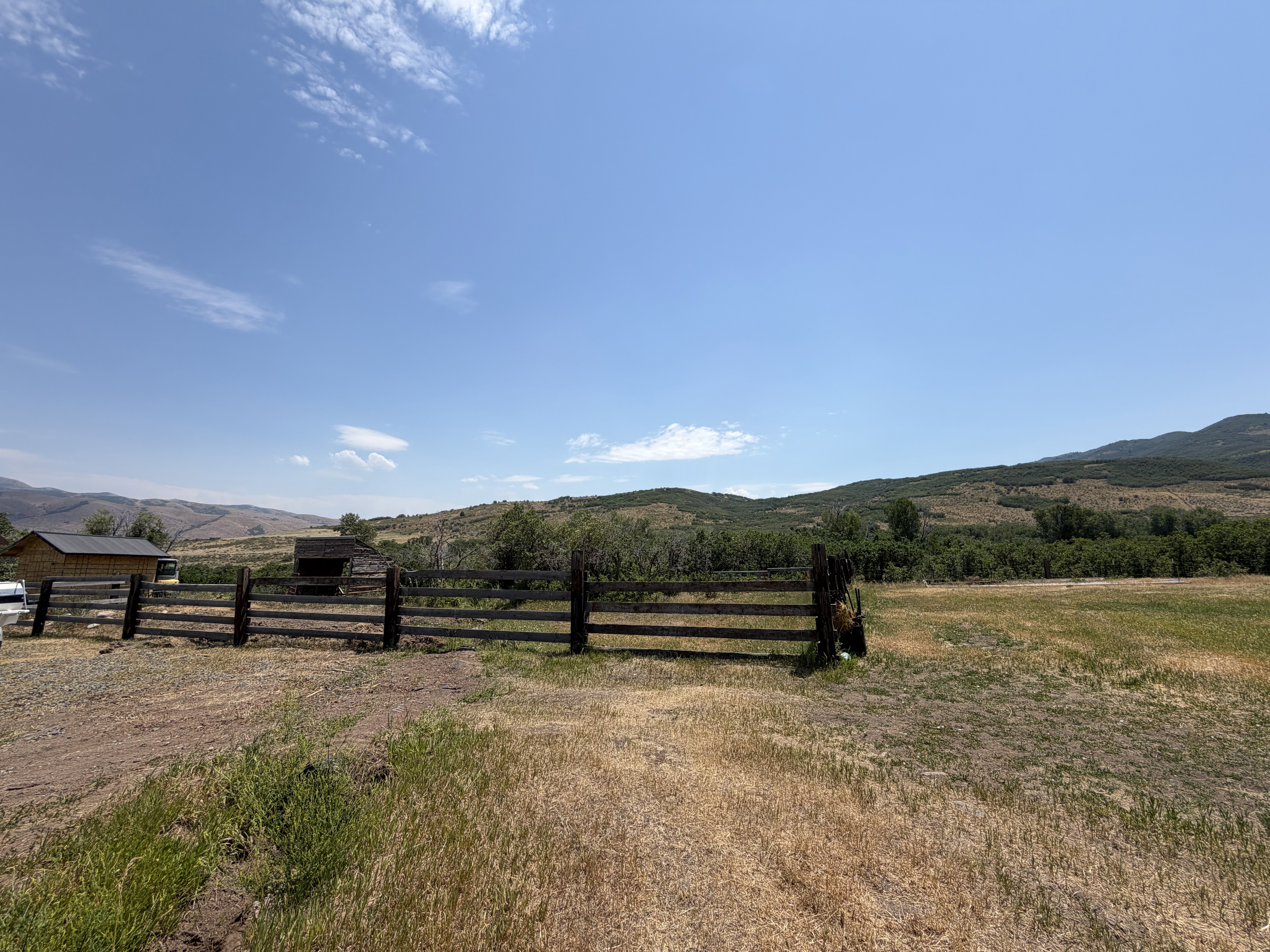 Expansive fenced area with a single-story structure and distant mountain scenery