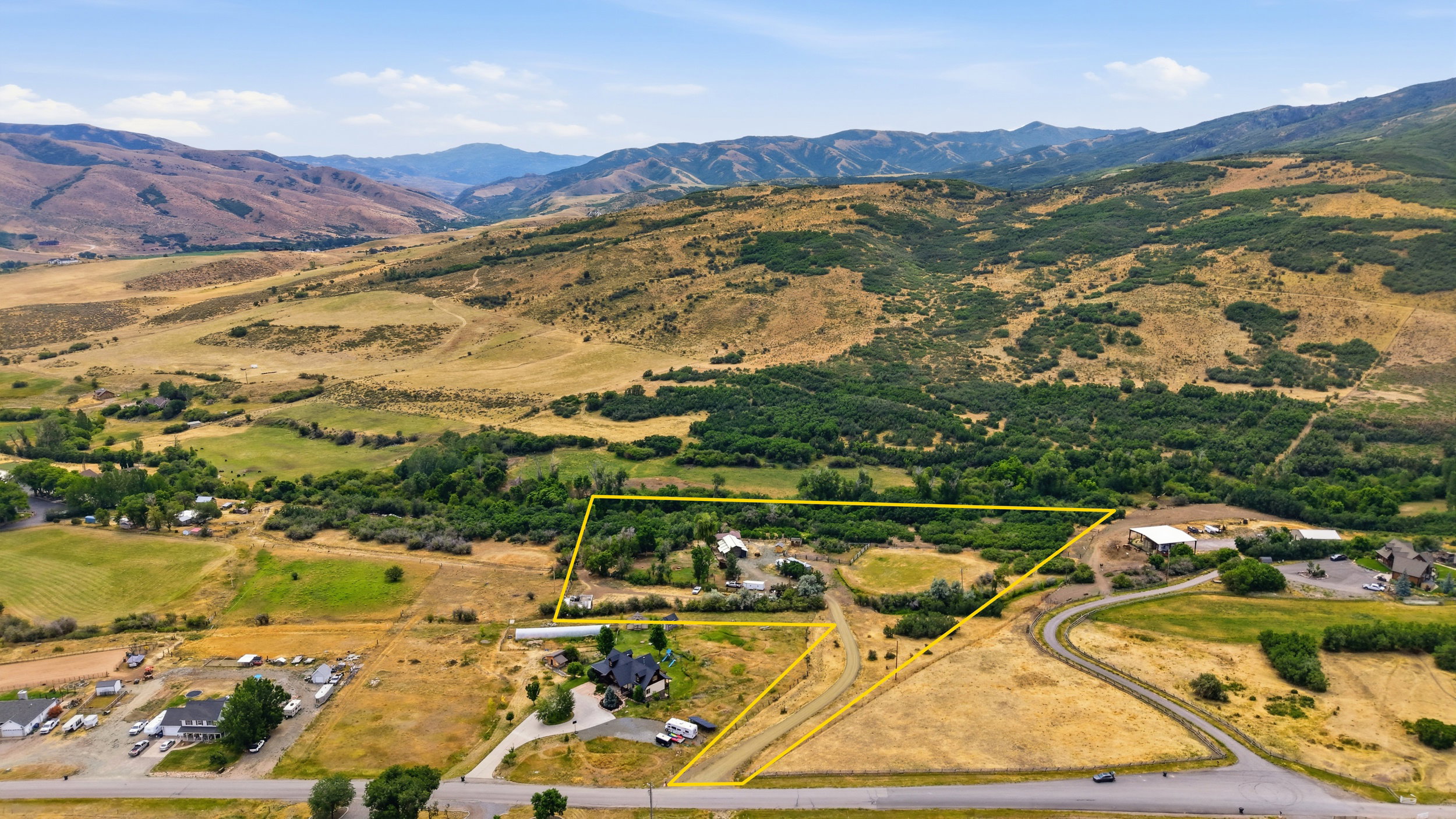 Expansive rural property featuring multiple structures, open land, and mountain backdrops