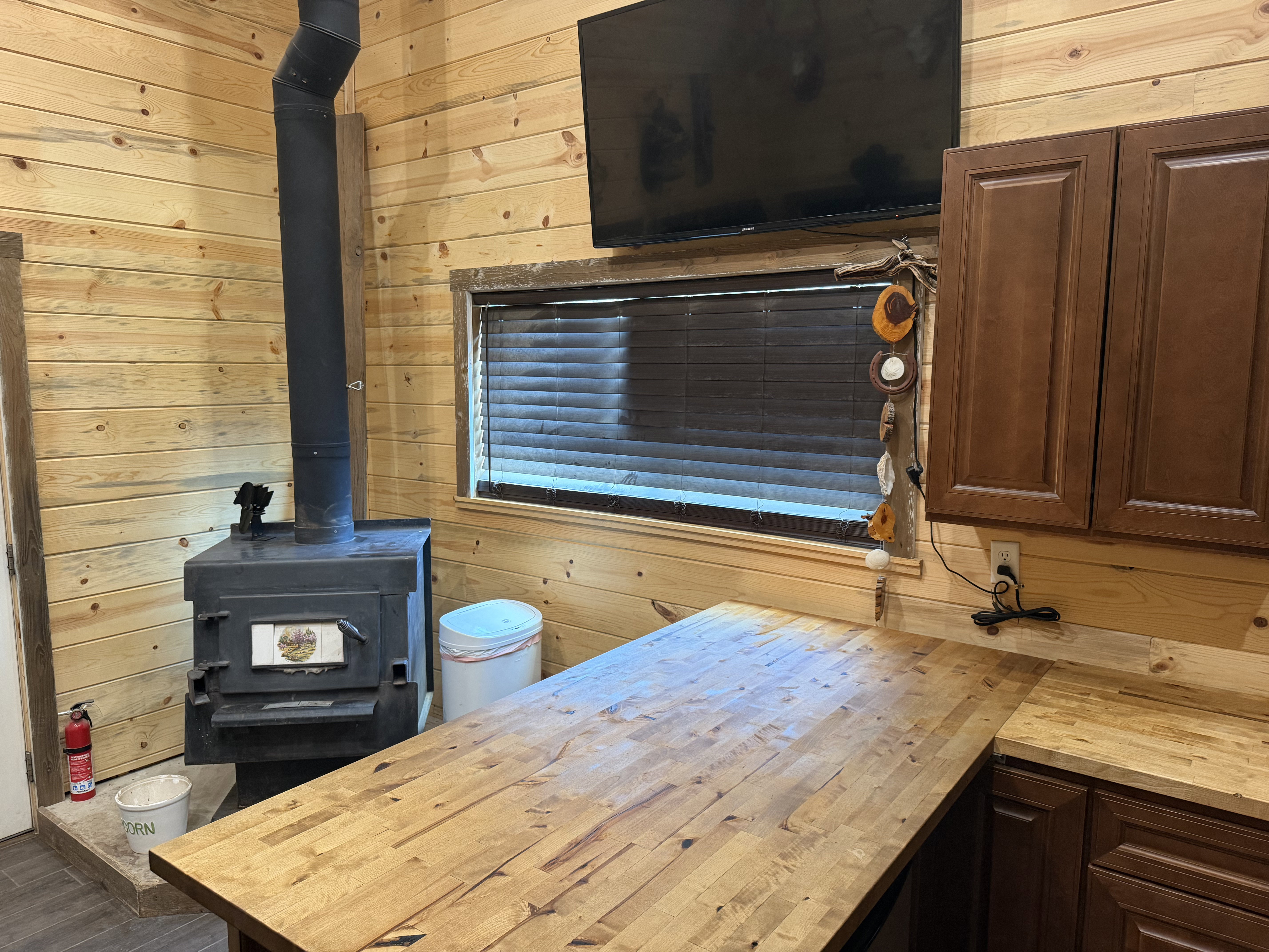Wood-paneled interior featuring a black wood-burning stove with metal flue and a built-in window with dark blinds