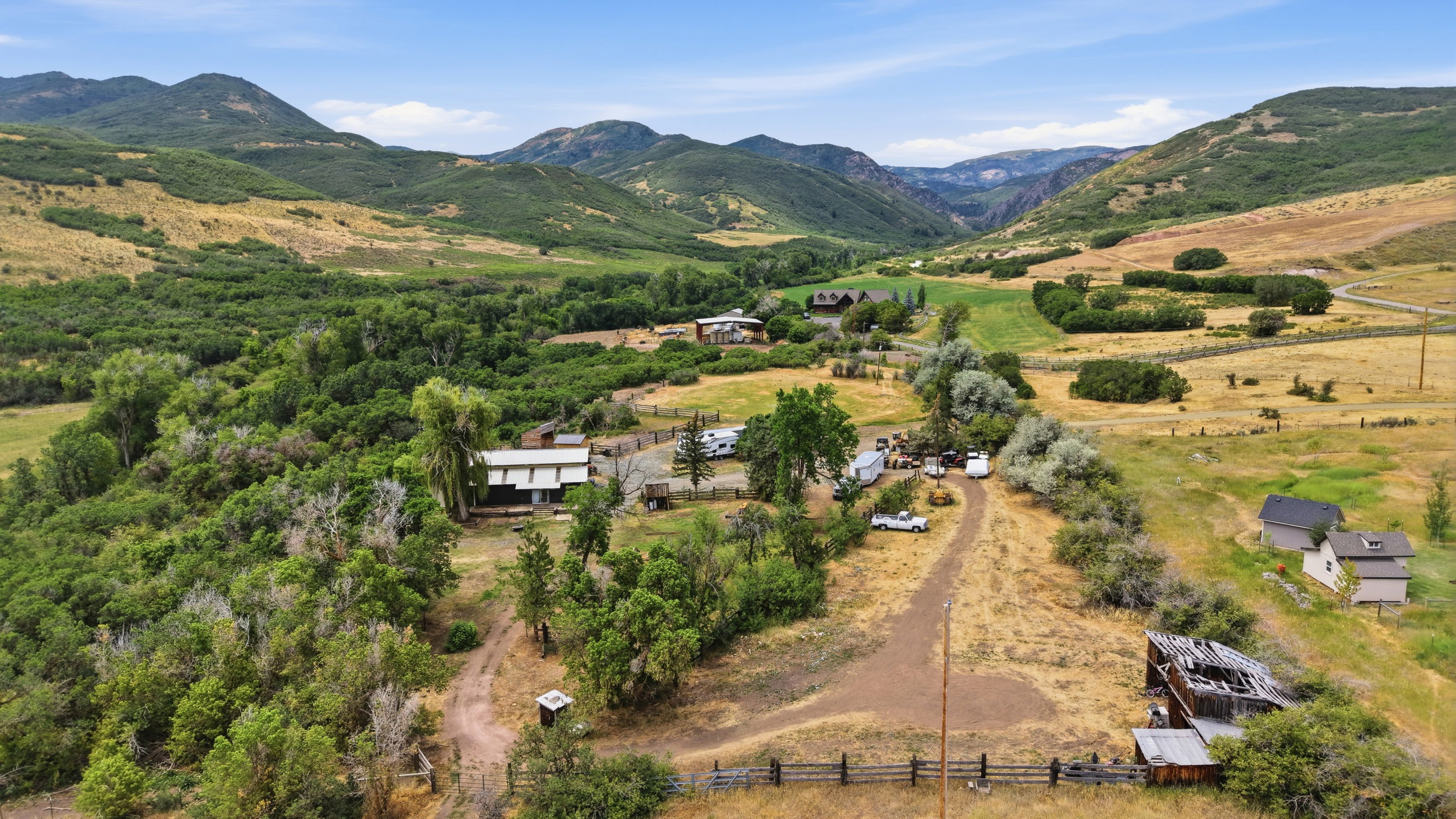 Expansive rural landscape featuring multiple structures, open fields, and abundant mature trees