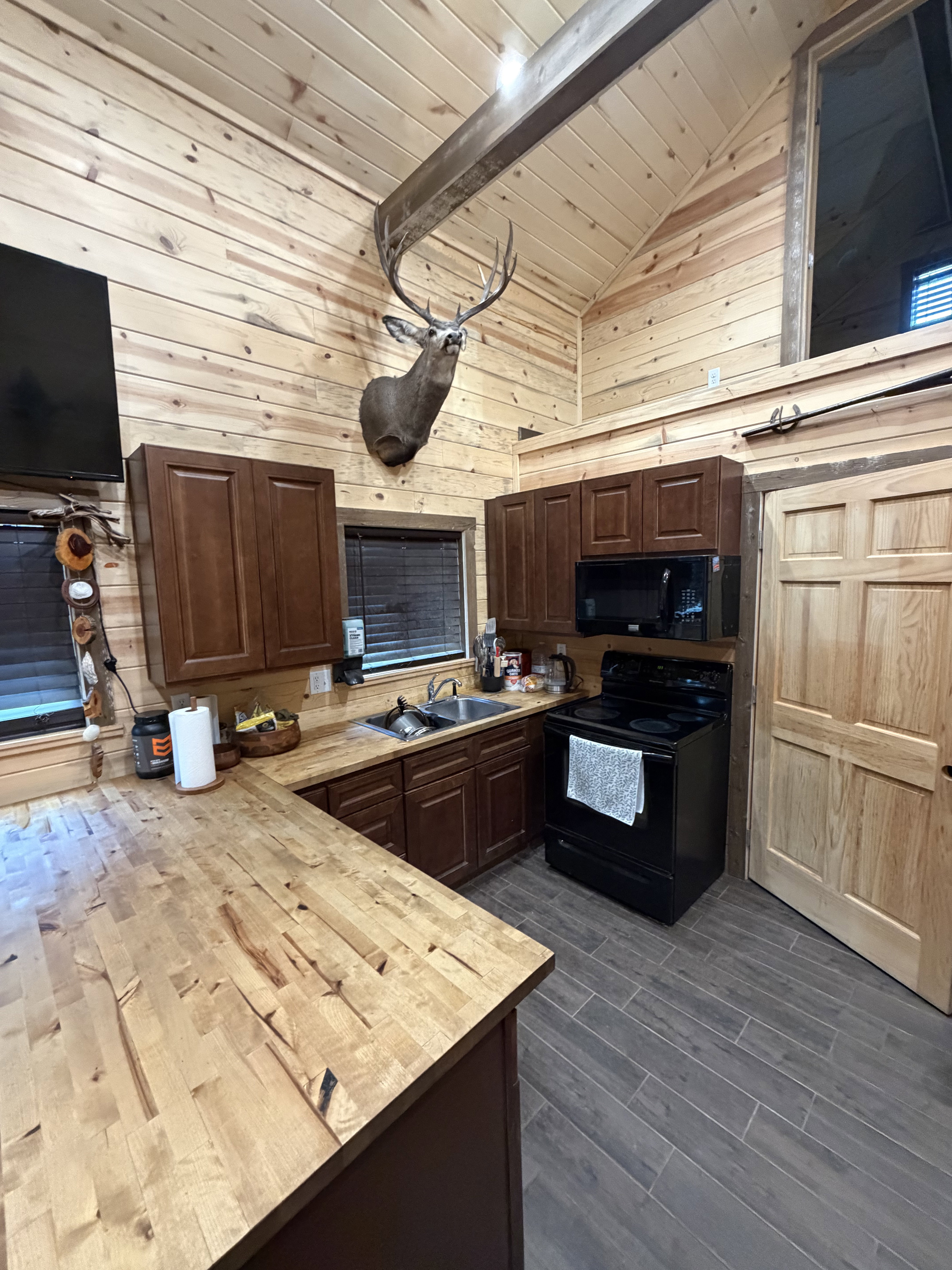 Vaulted planked wood ceiling with exposed beam, wood-finish wall paneling, and wood-finish flooring
