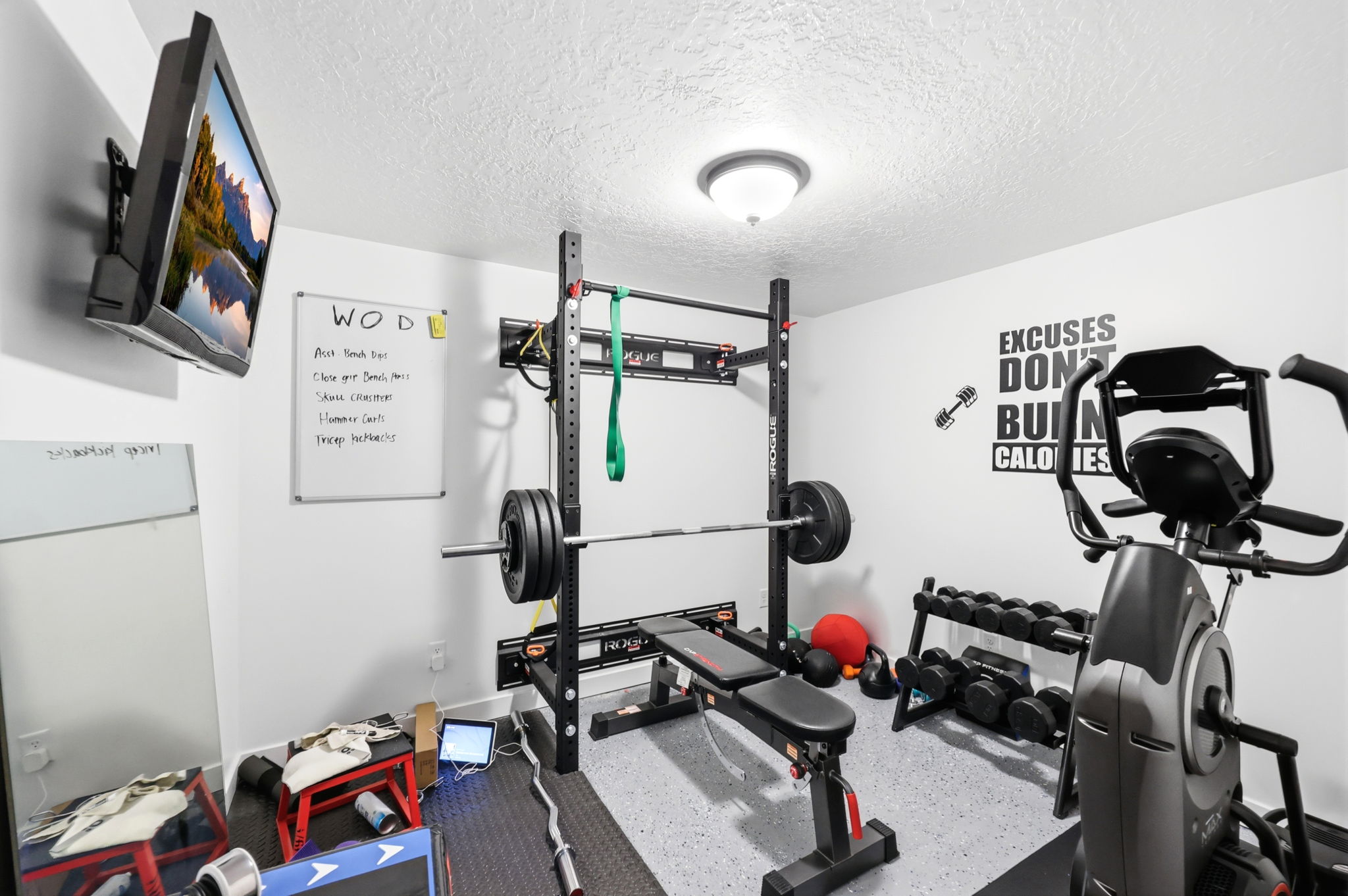 Dedicated fitness space featuring light gray walls, textured white ceiling, and a flush-mount ceiling light