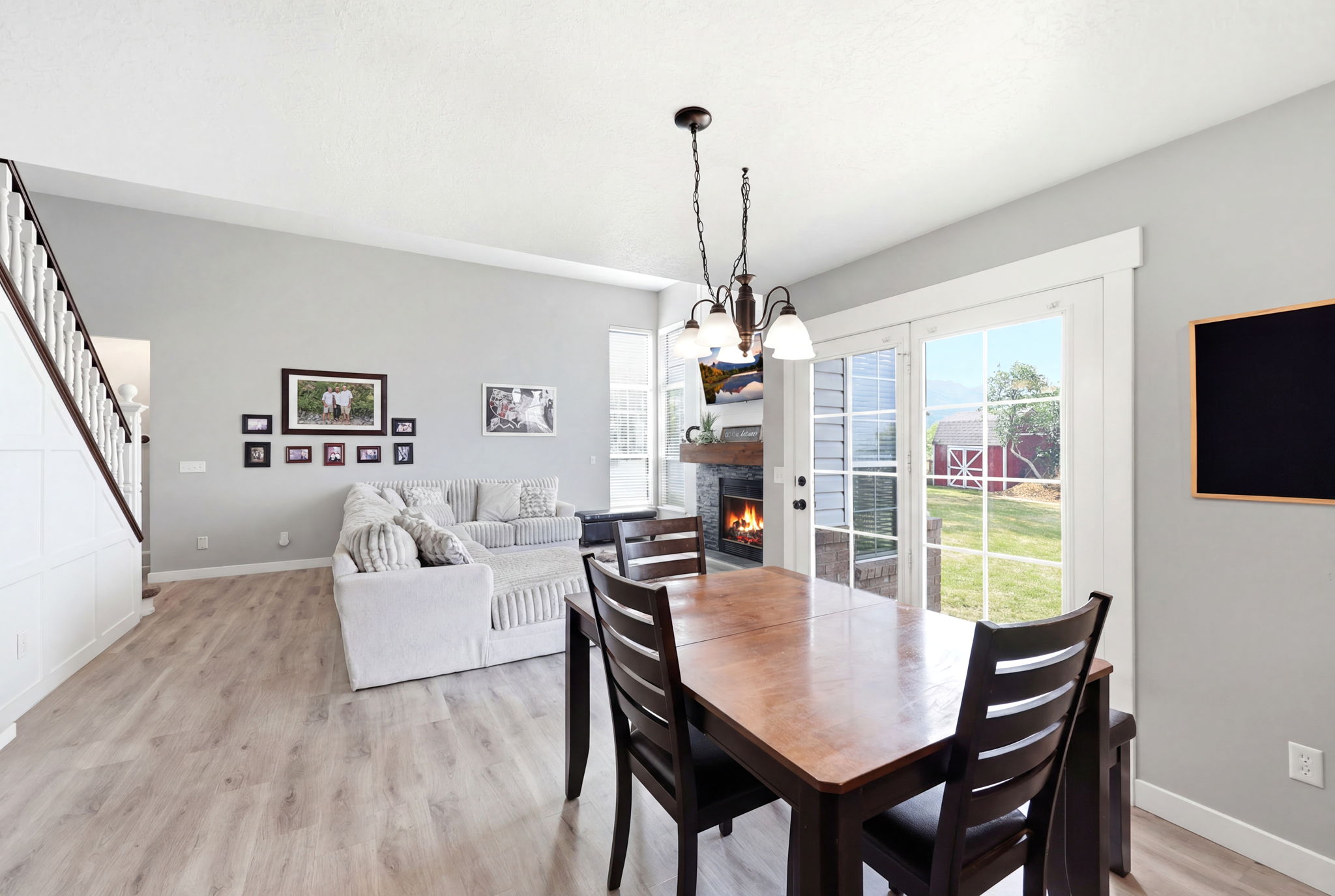 Open concept living area featuring wood-finish flooring, a modern fireplace, white trim details, and sliding glass doors