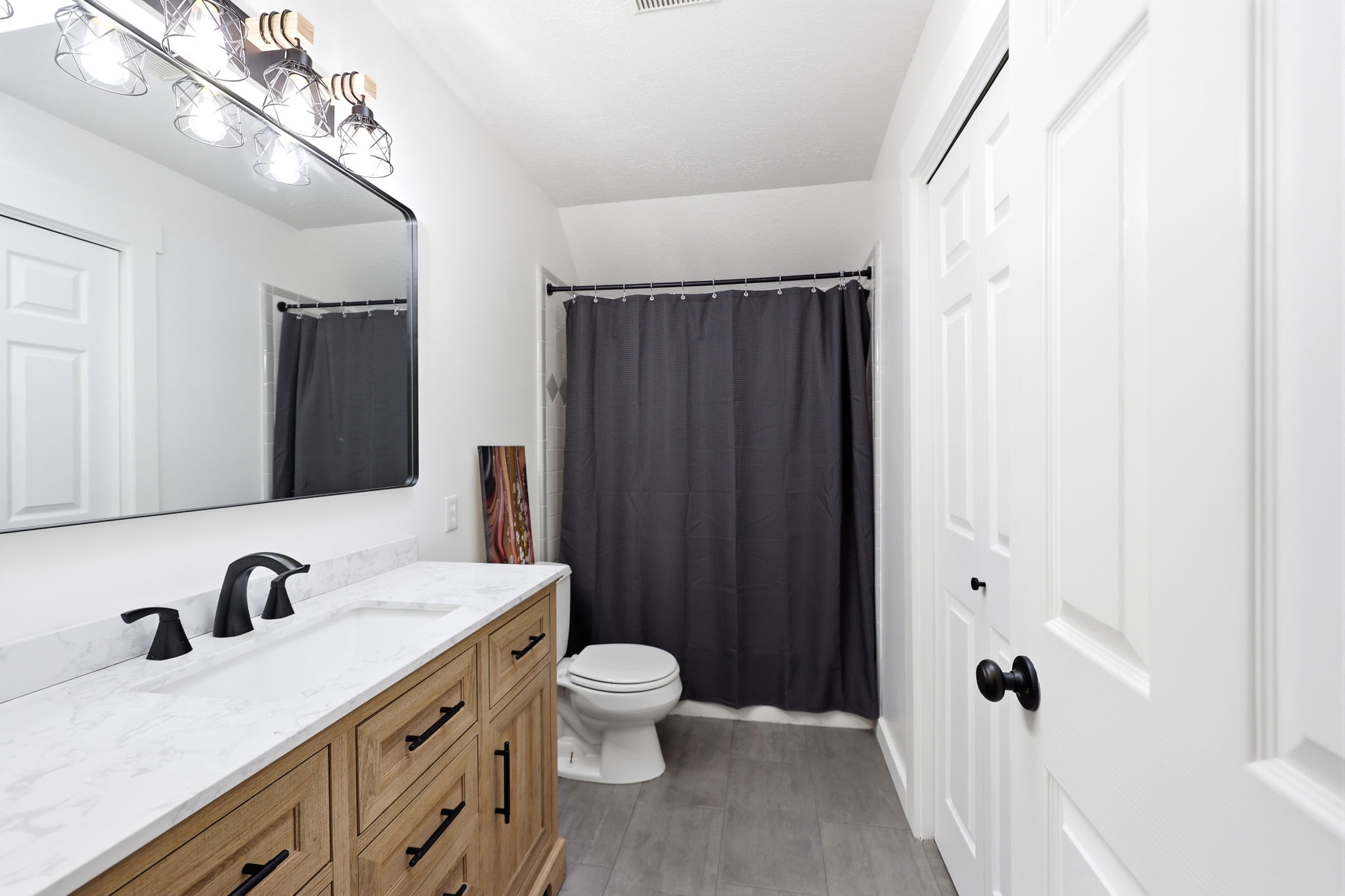 Bathroom featuring a light wood-finish vanity with a white countertop and matte black fixtures
