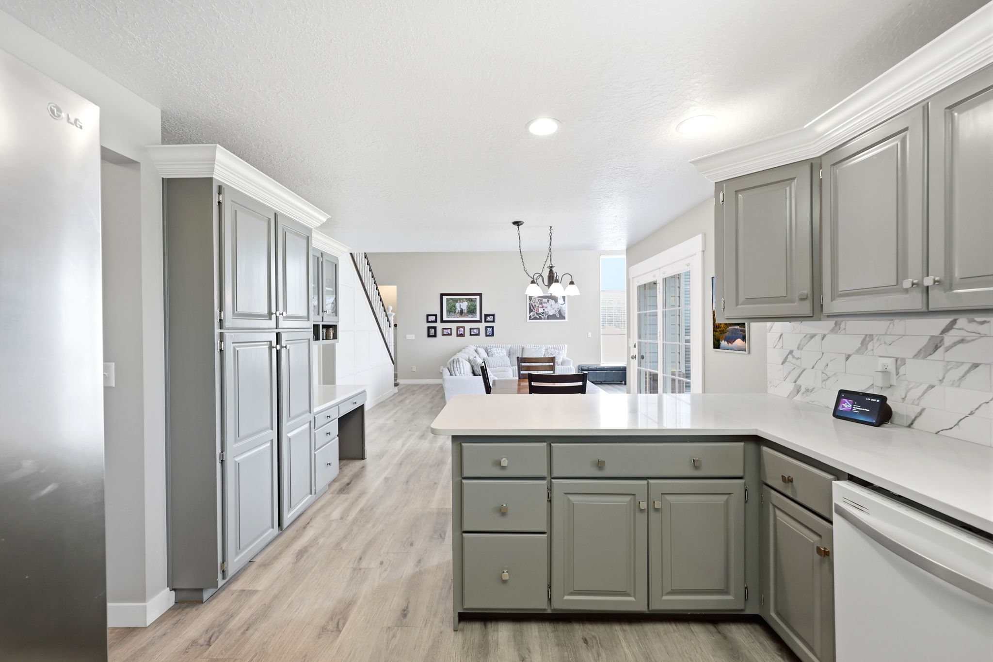 Contemporary kitchen featuring light gray cabinetry, light wood-finish flooring, white countertops, and a white marble-patterned backsplash