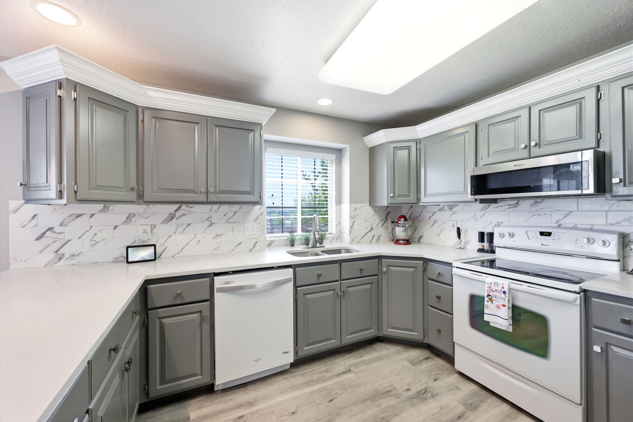 Modern kitchen featuring light gray cabinetry, white countertops, and a white subway tile backsplash with gray veining