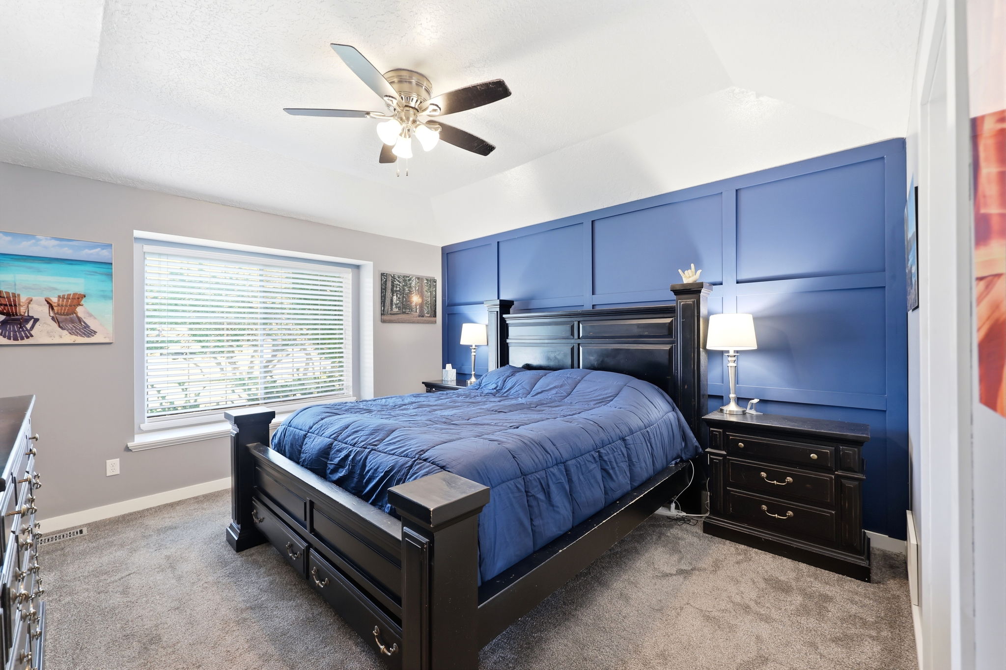 Bedroom featuring a decorative accent wall, vaulted ceiling, and ceiling fan