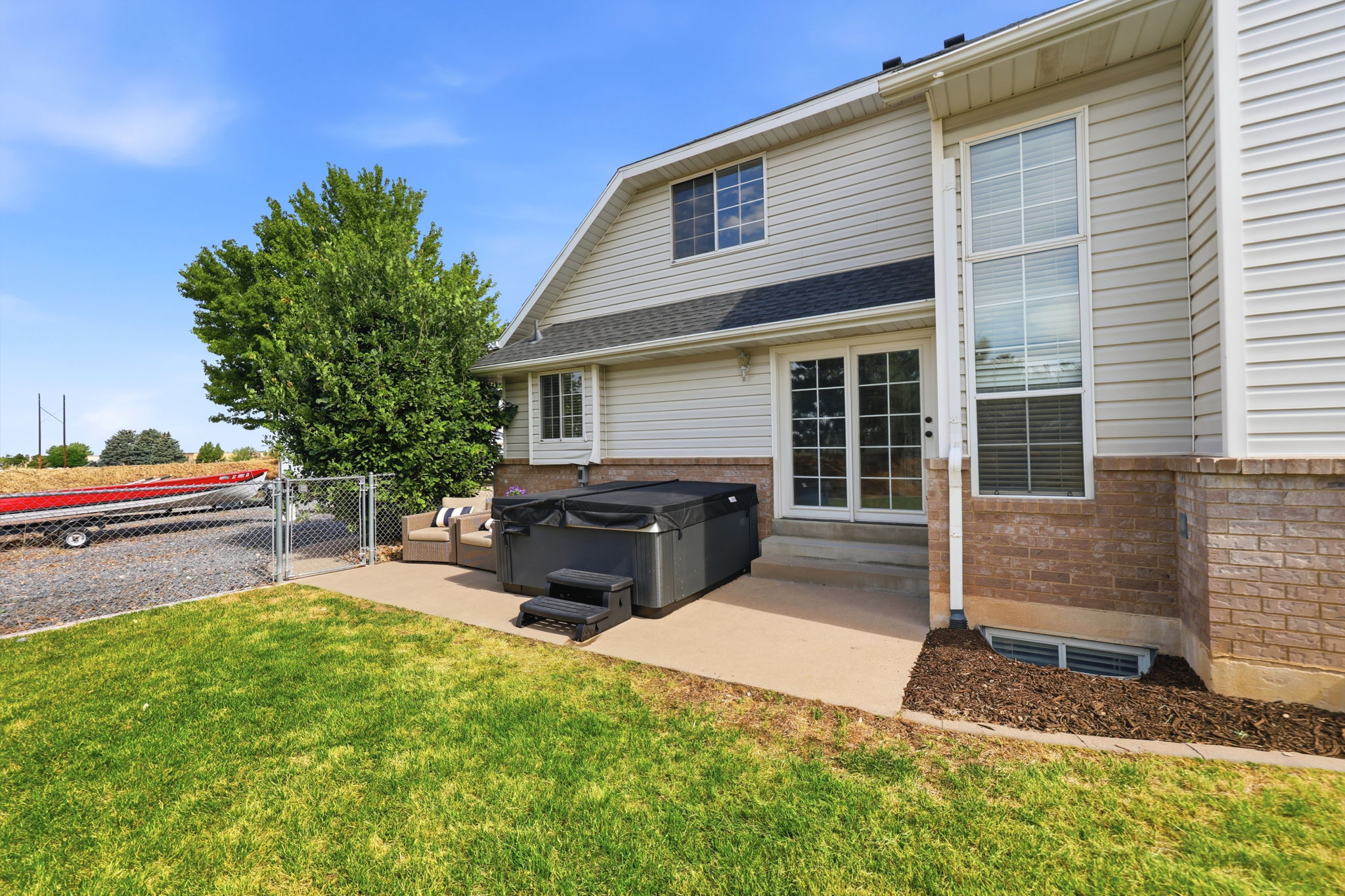 Expansive backyard featuring a concrete patio, green lawn, and mature tree